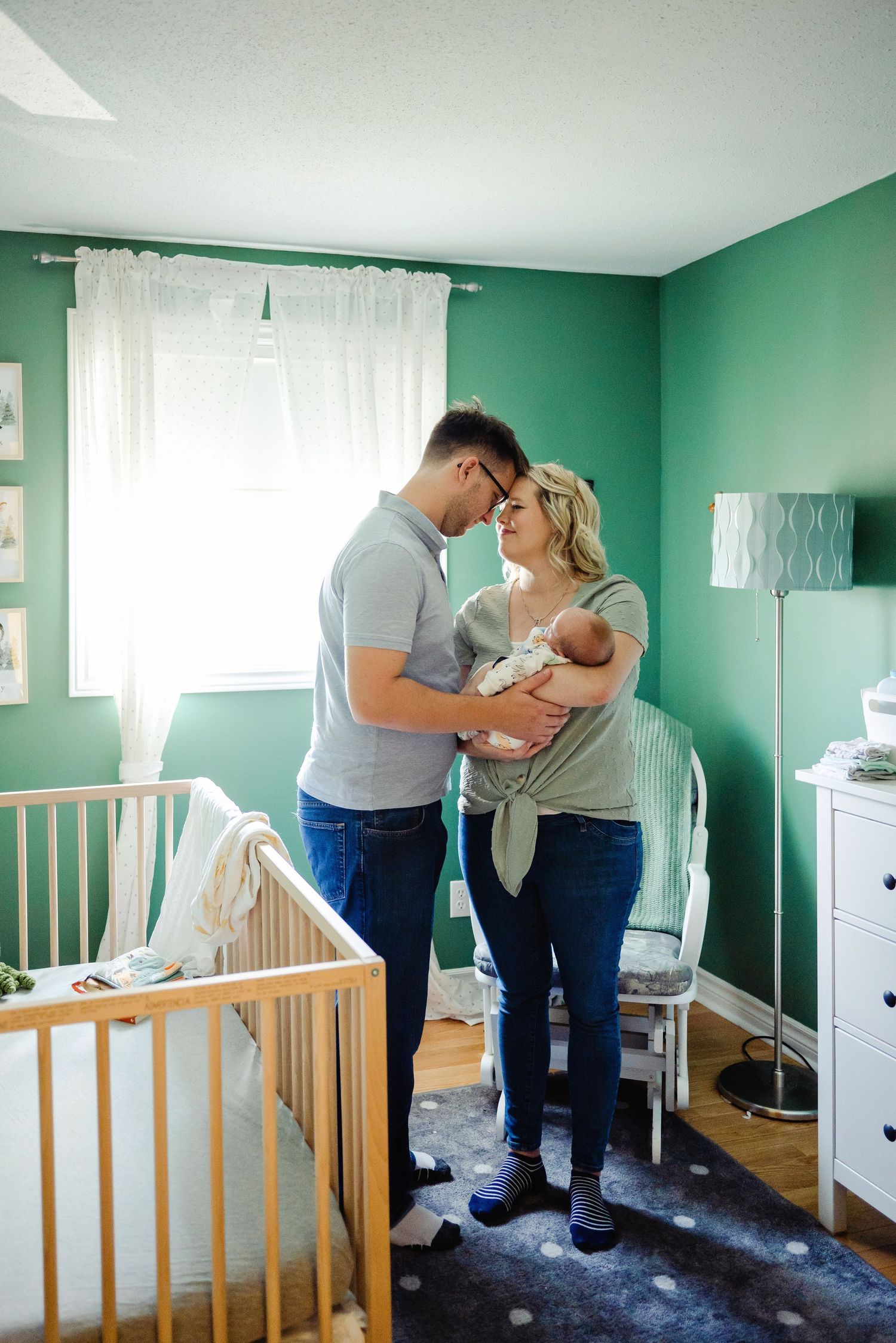Mom and dad holding newborn in nursery. Ottawa Newborn Photography. Ottawa Family Photography