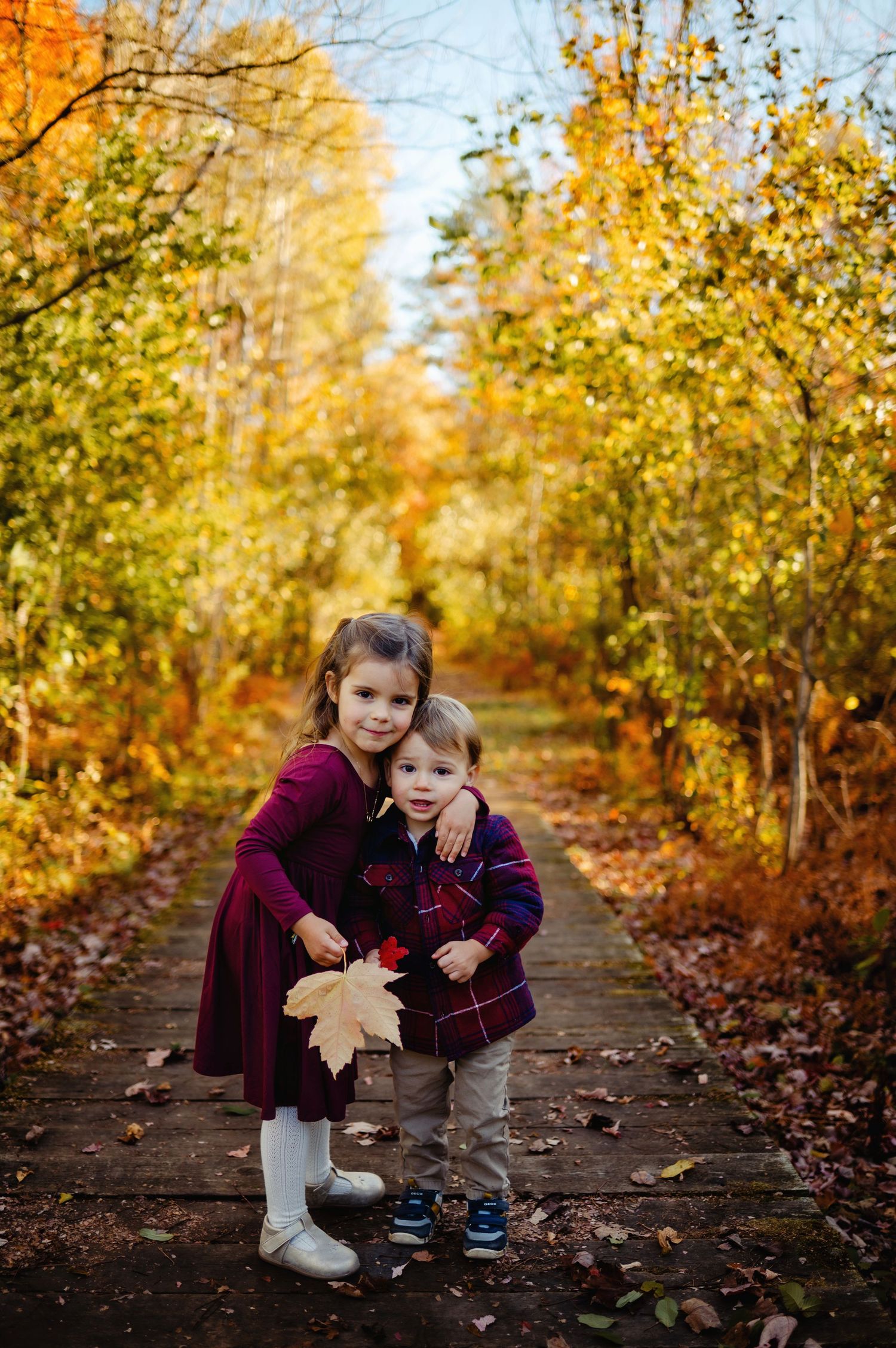 Sister and brother huggings on boardwalk in the forest. Ottawa Family Photography.