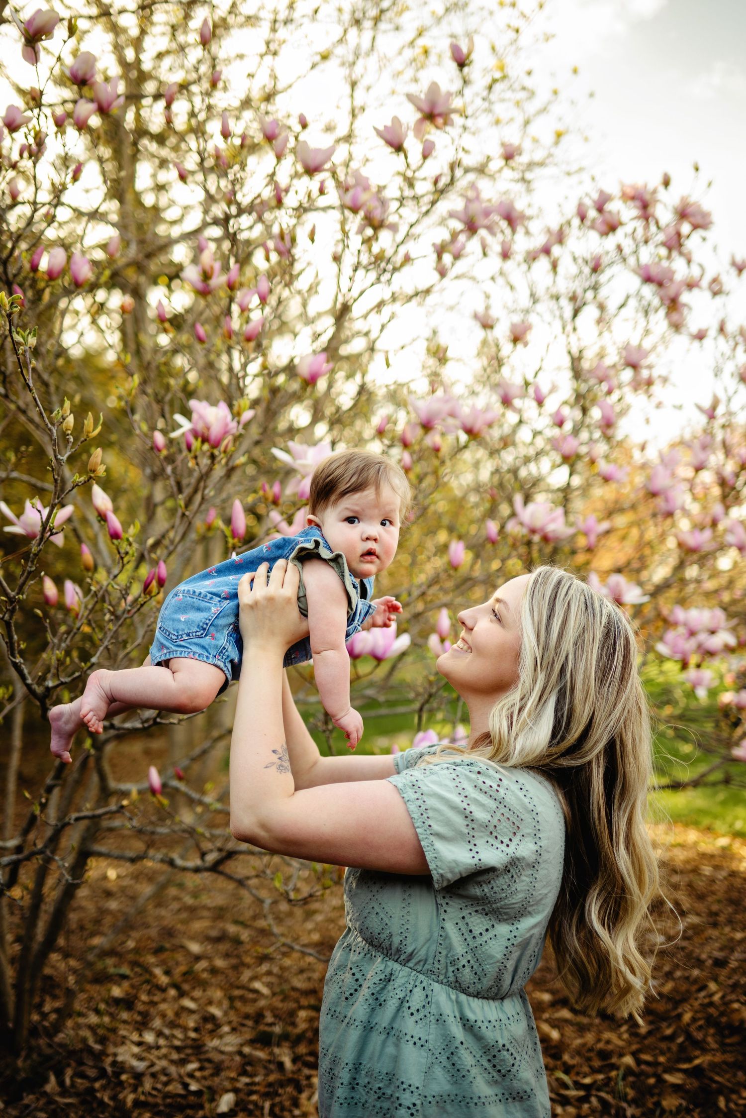Mom holding baby up by cherry blossoms. Ottawa Family Photographer. Ottawa Mini Sessions Photographer