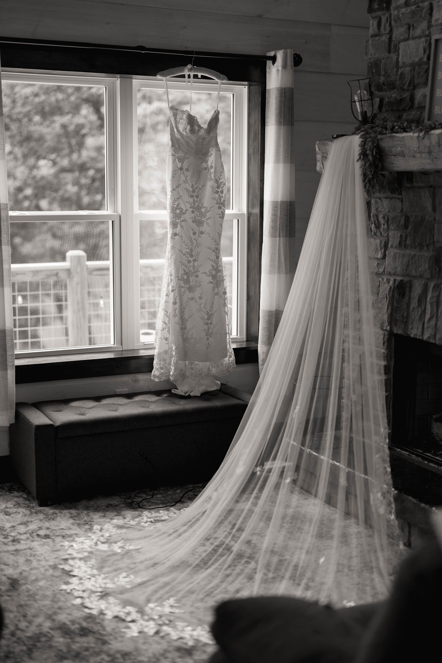 Elegant wedding dress with long flowing veil displayed near window in natural light.