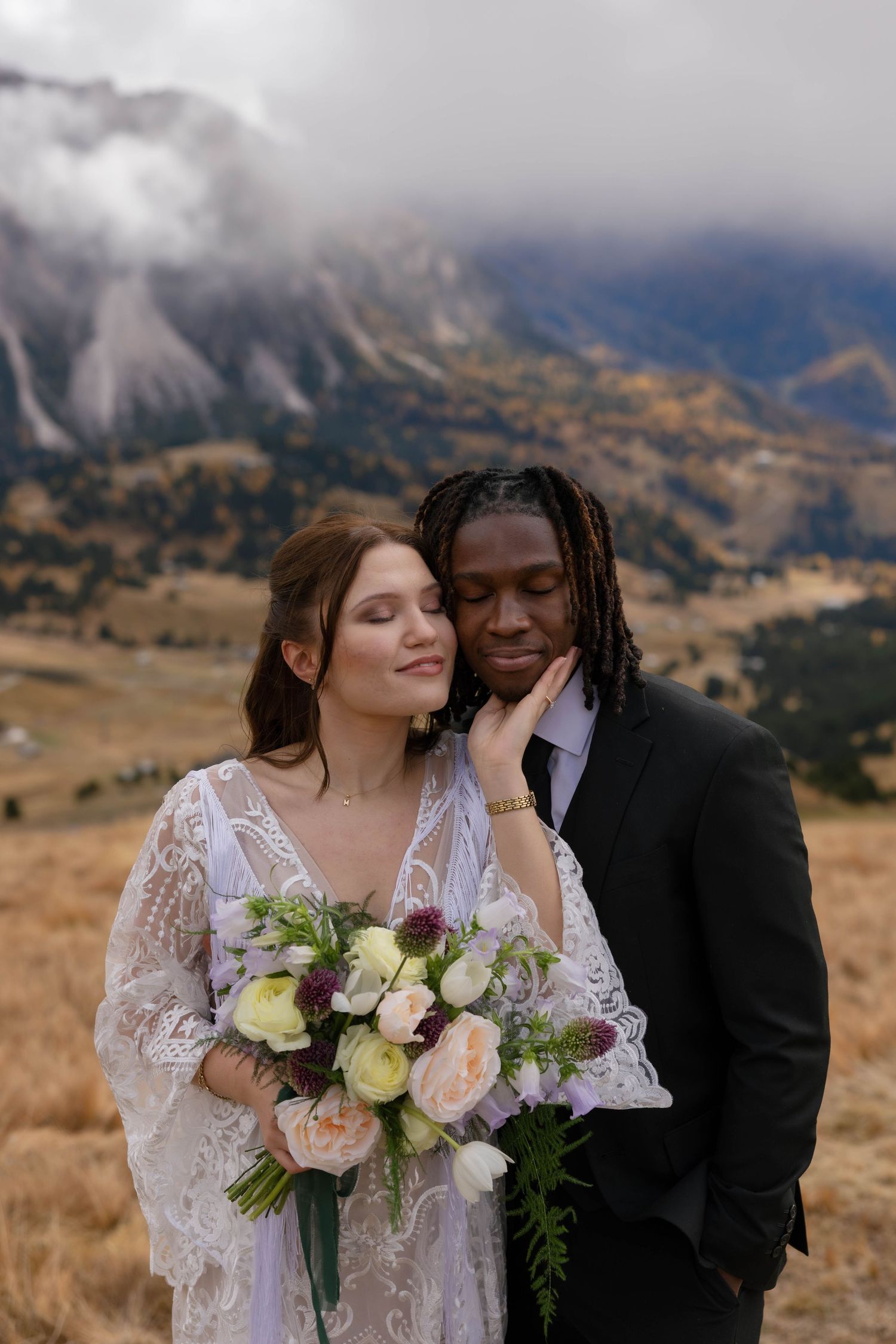 Intimate wedding portraits with mountain landscape and bouquet of flowers in the Dolomites