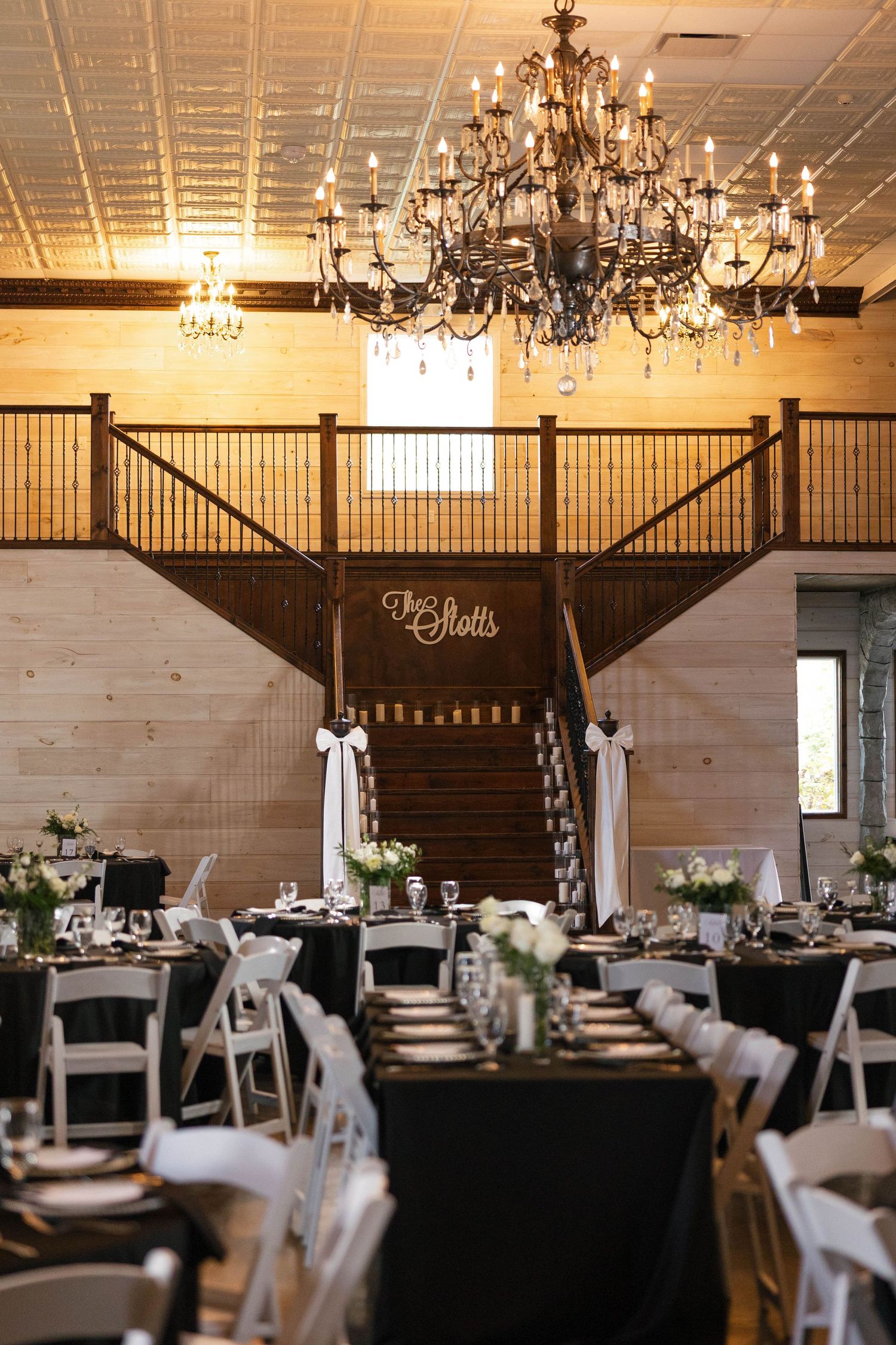 Rustic wedding reception venue with chandeliers and elegant table settings.