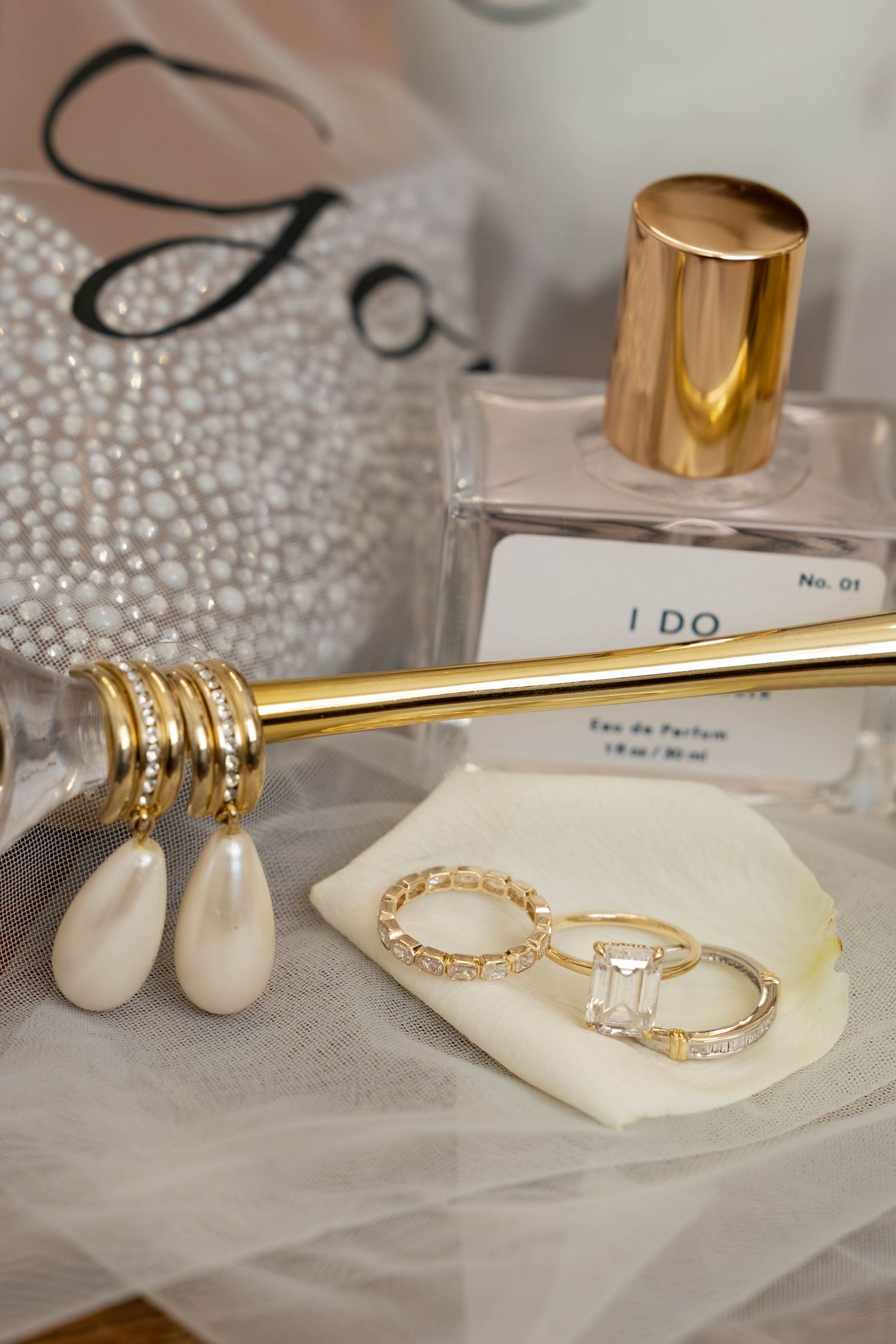 Gold wedding rings and jewelry displayed on white fabric with pearl details.