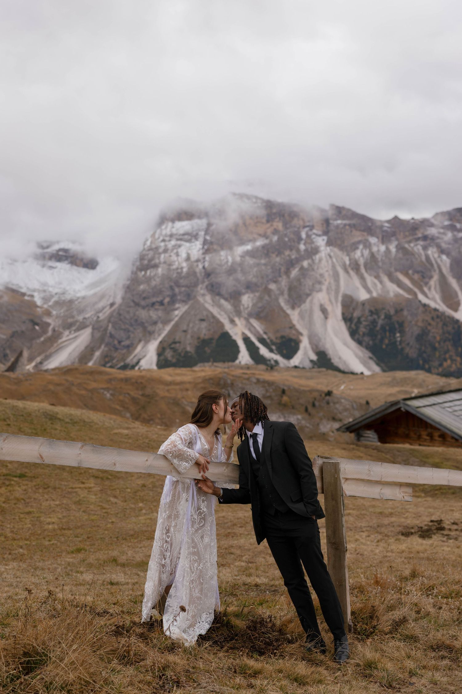 Wedding couple posing playfully in front of dramatic mountain landscape.