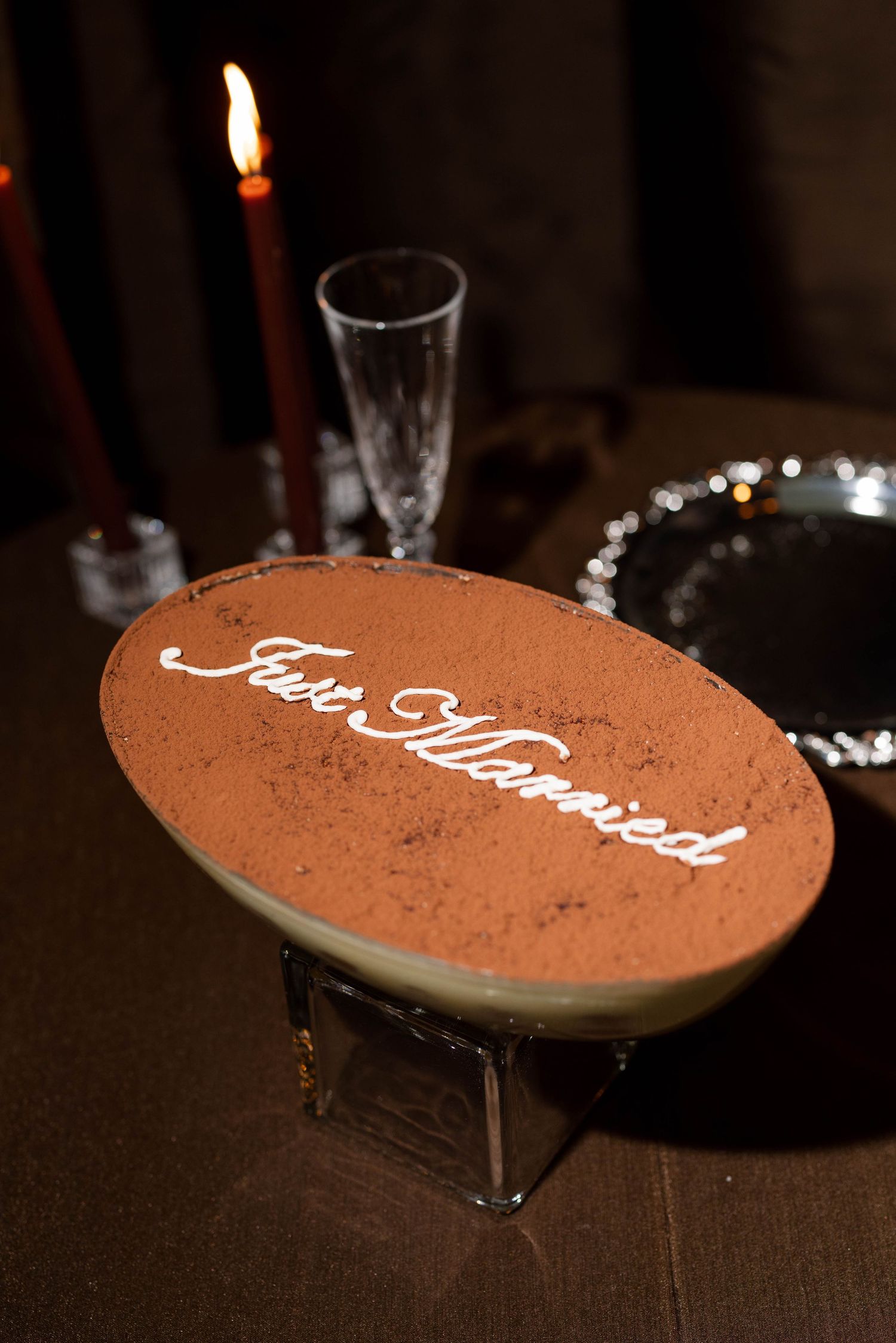 Close-up of a tiramisu dessert with text written in icing on cocoa background.
