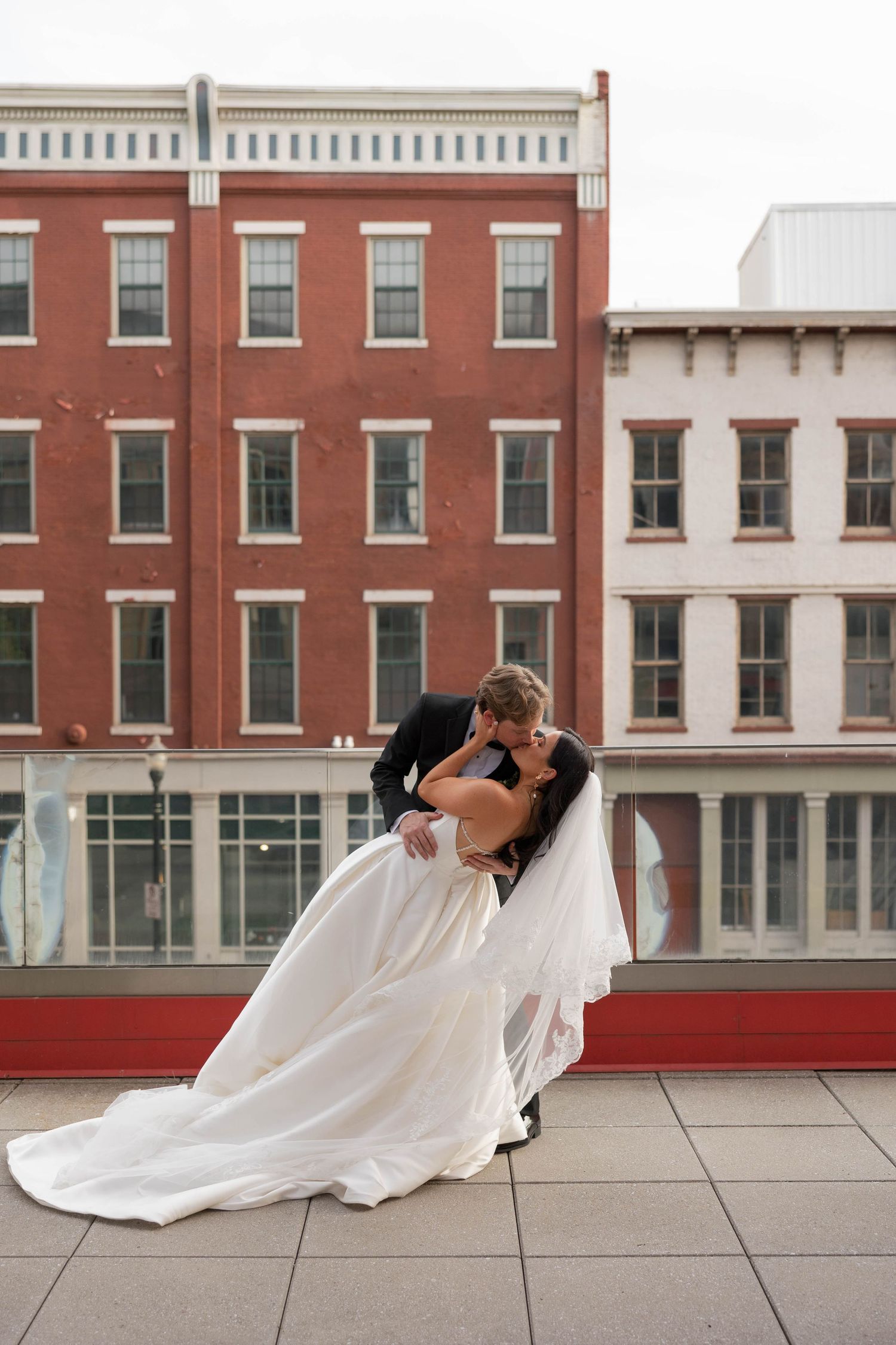 Wedding couple performs dramatic dips against a backdrop of historic red brick buildings in downtown Louisville kentucky