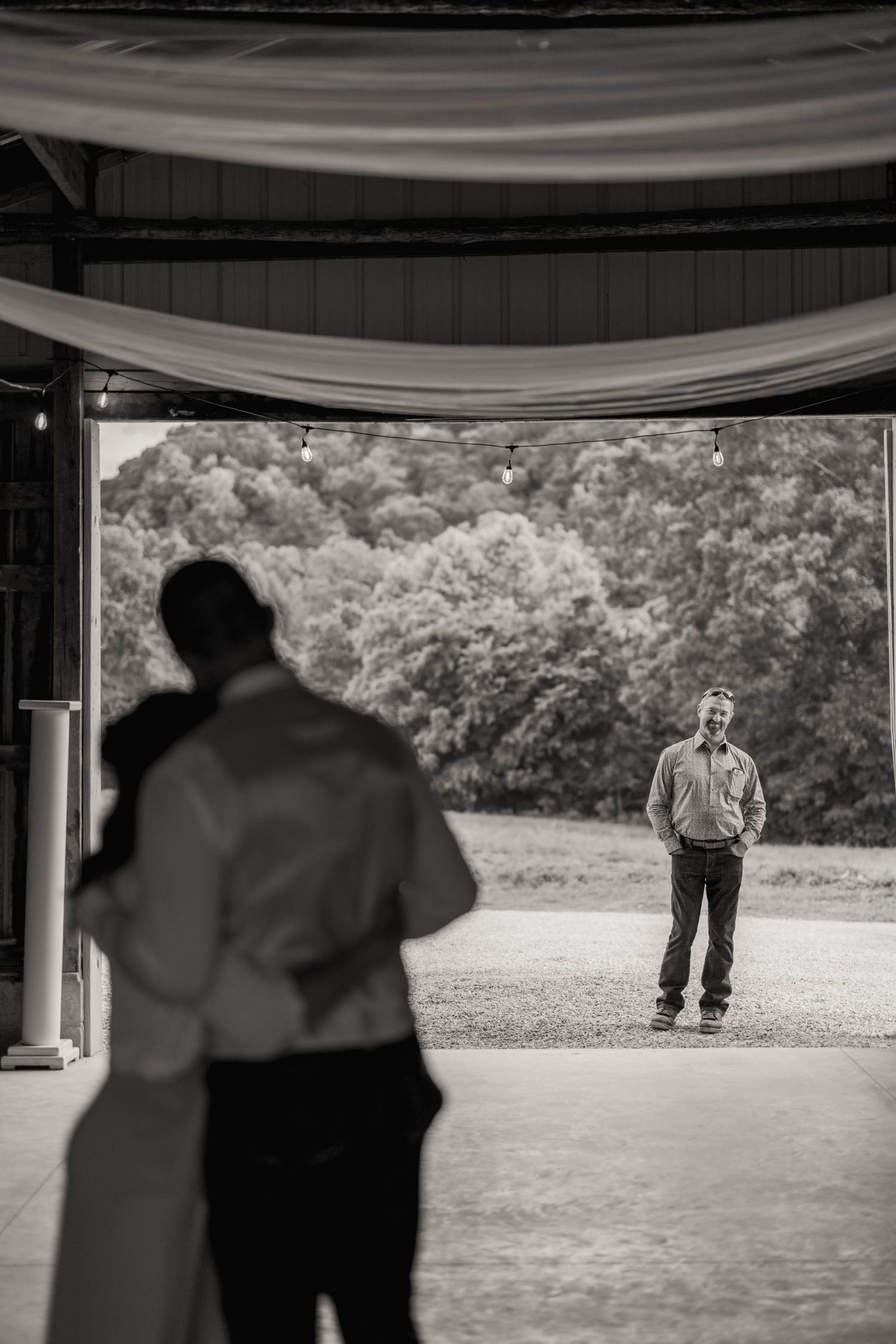 black and white photo of a father watching groom and moms first dance