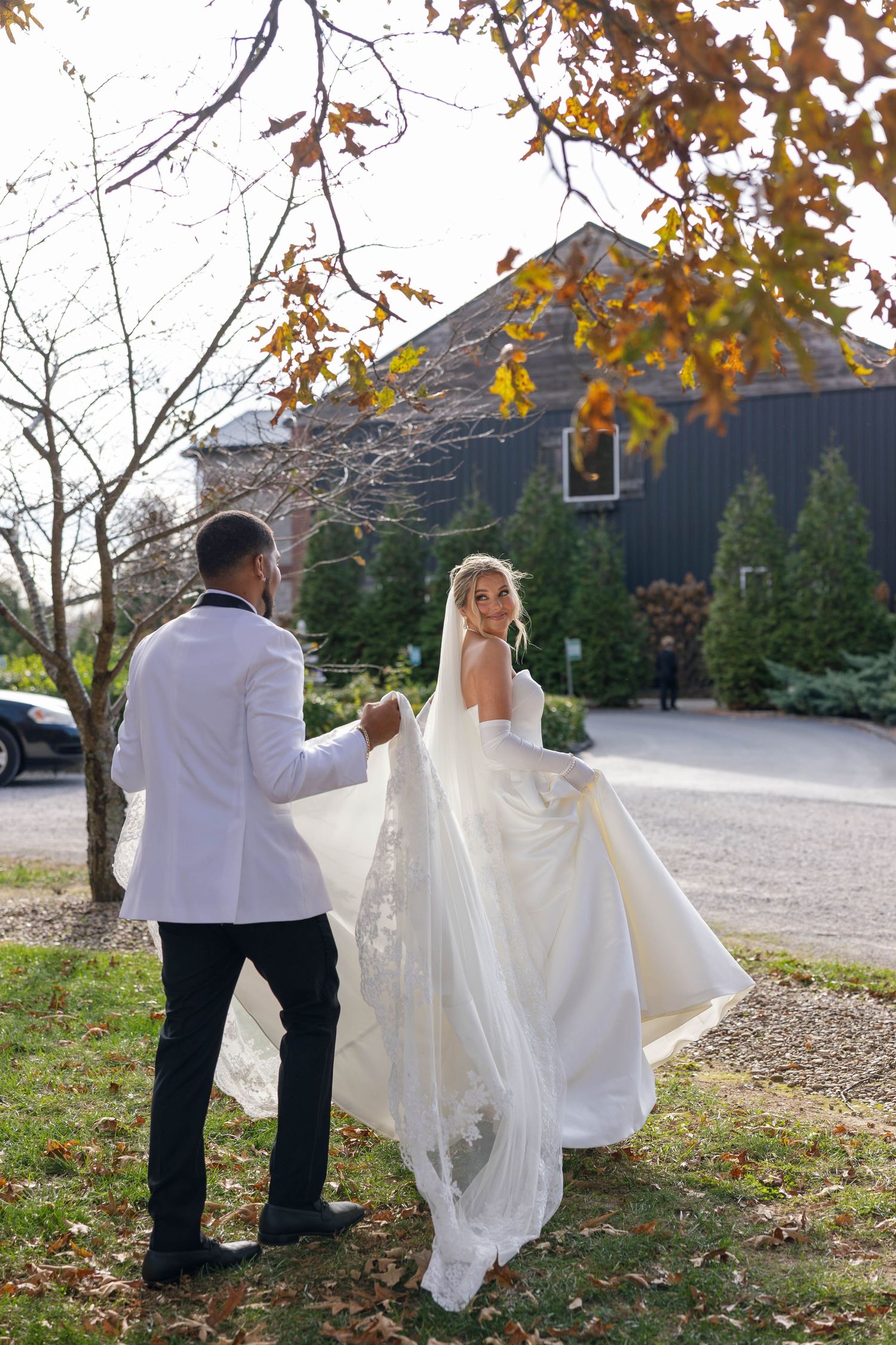 Couple walking together outdoors with autumn leaves and flowing wedding dress.