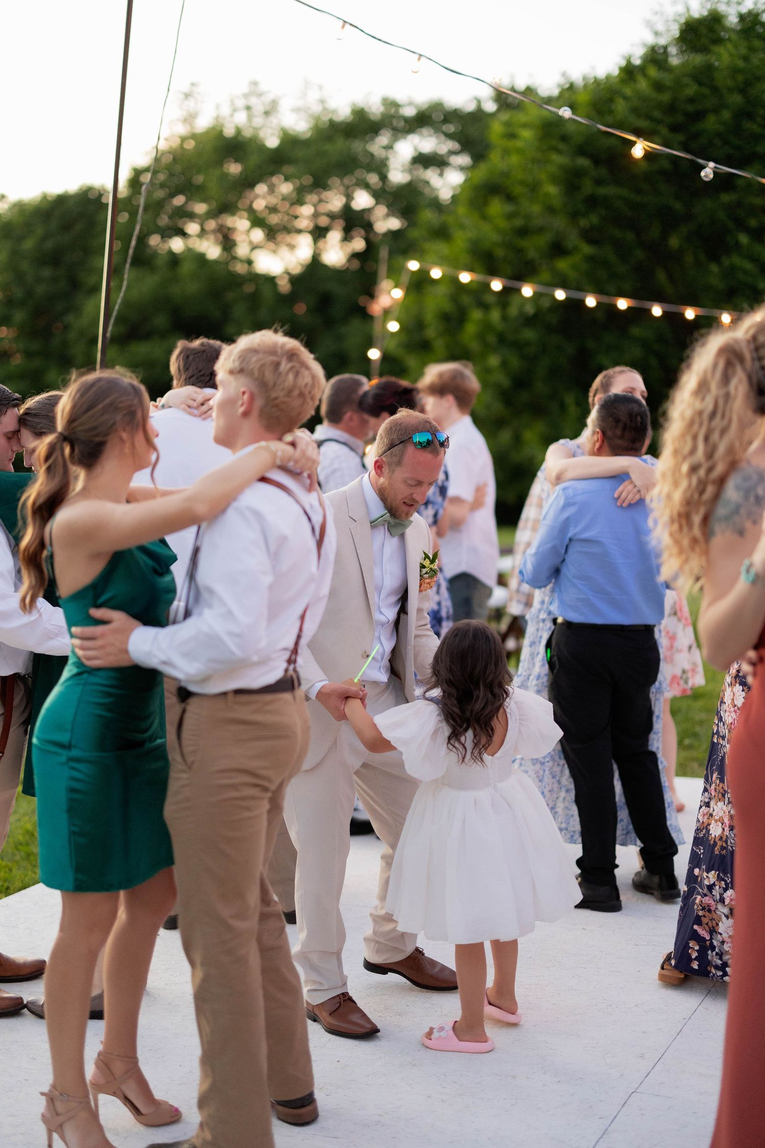 Wedding guests dancing together on an outdoor dance floor at sunset.