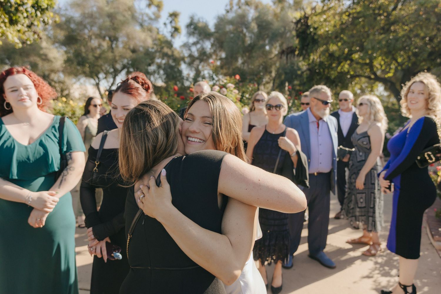 Wedding guests dance together in a line formation outdoors during a celebration event.