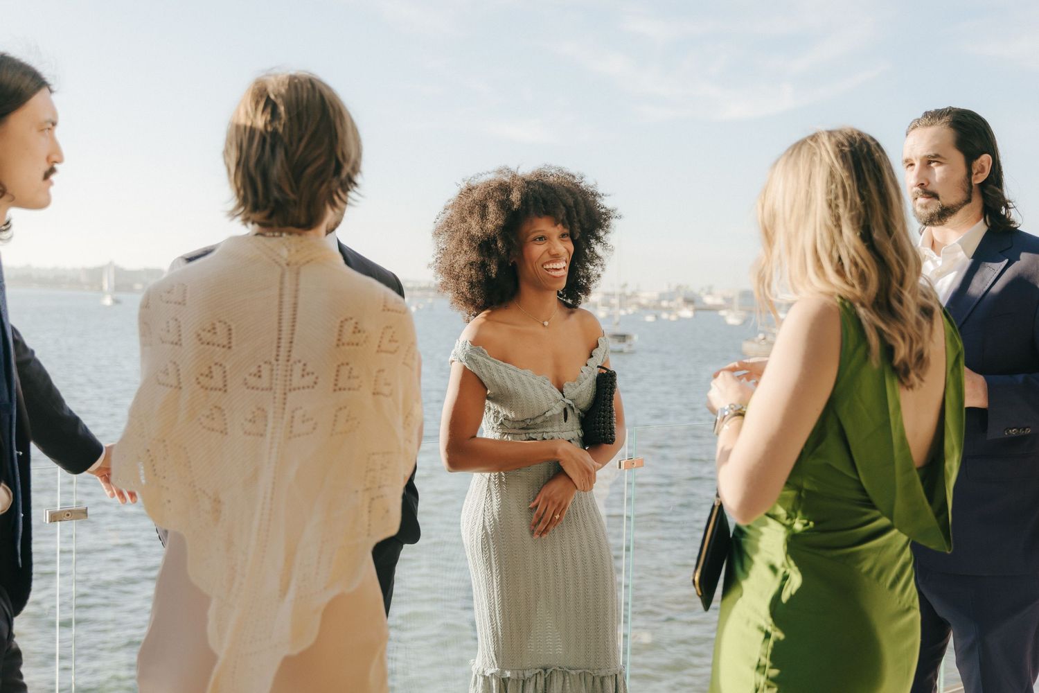 A collage of wedding guests in green and white dresses standing near a waterfront during an outdoor celebration.