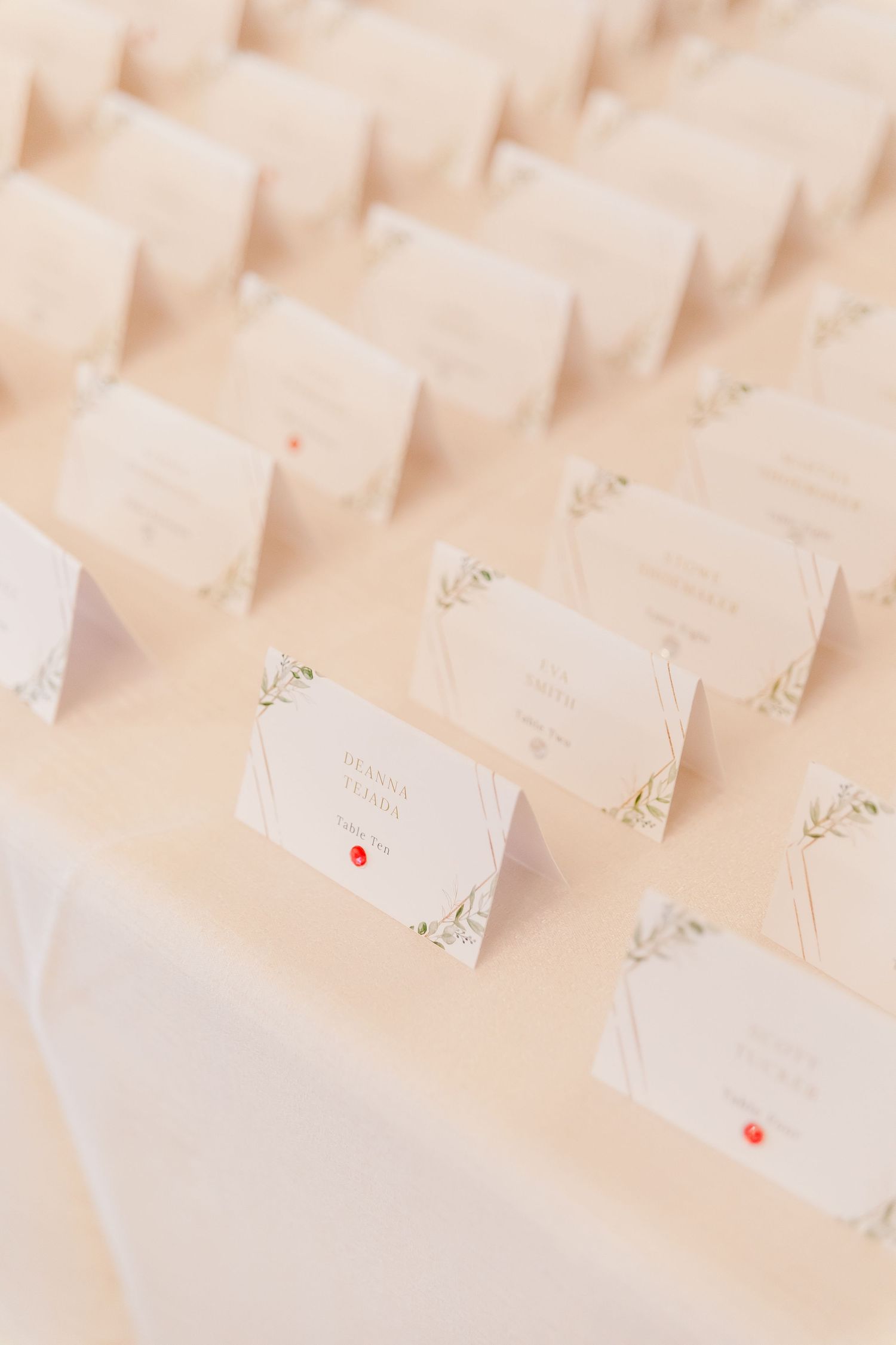 Rows of elegant white place cards arranged on a beige surface for wedding seating.