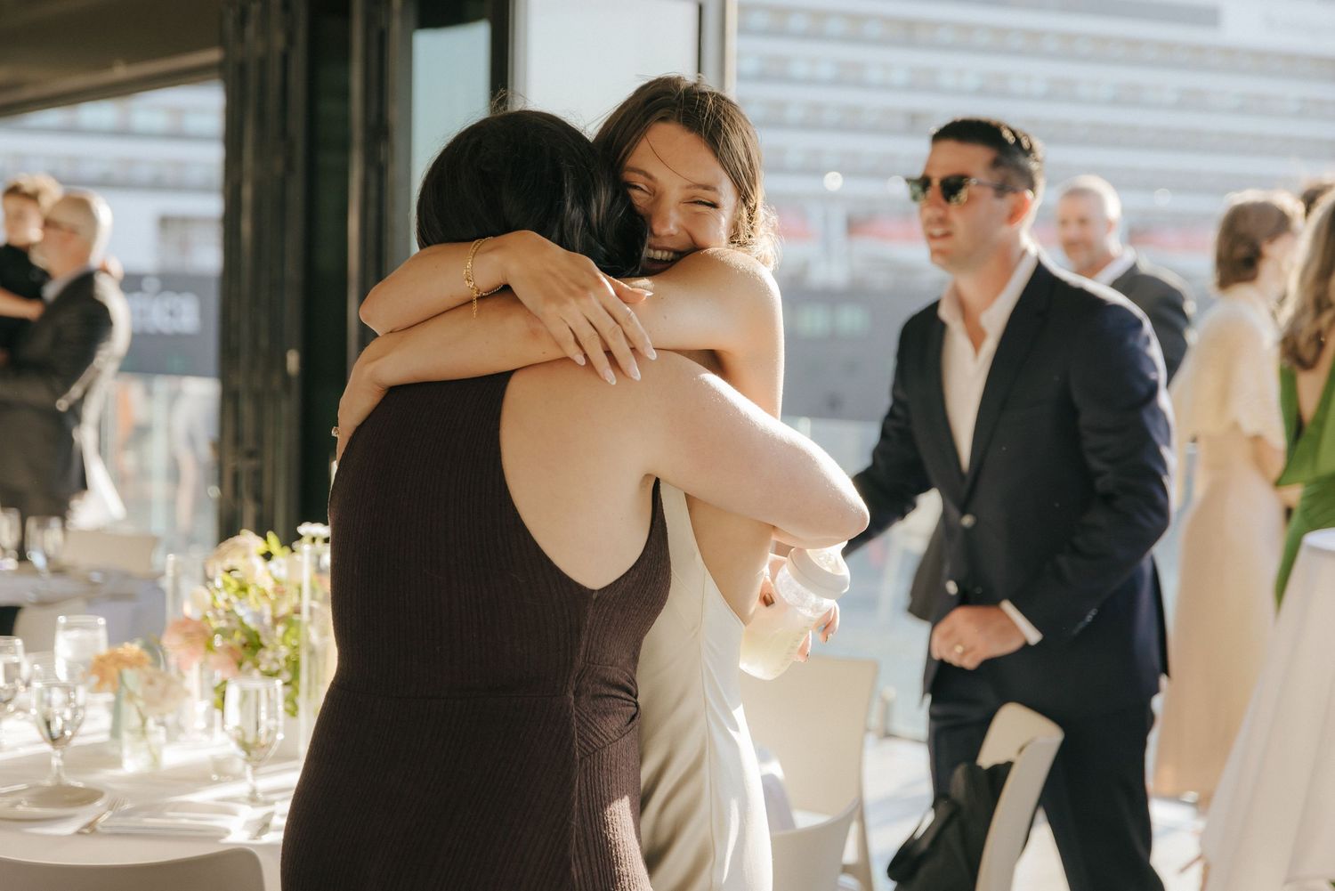 Wedding guests mingle and dance during an elegant outdoor reception with white decor and floral arrangements.