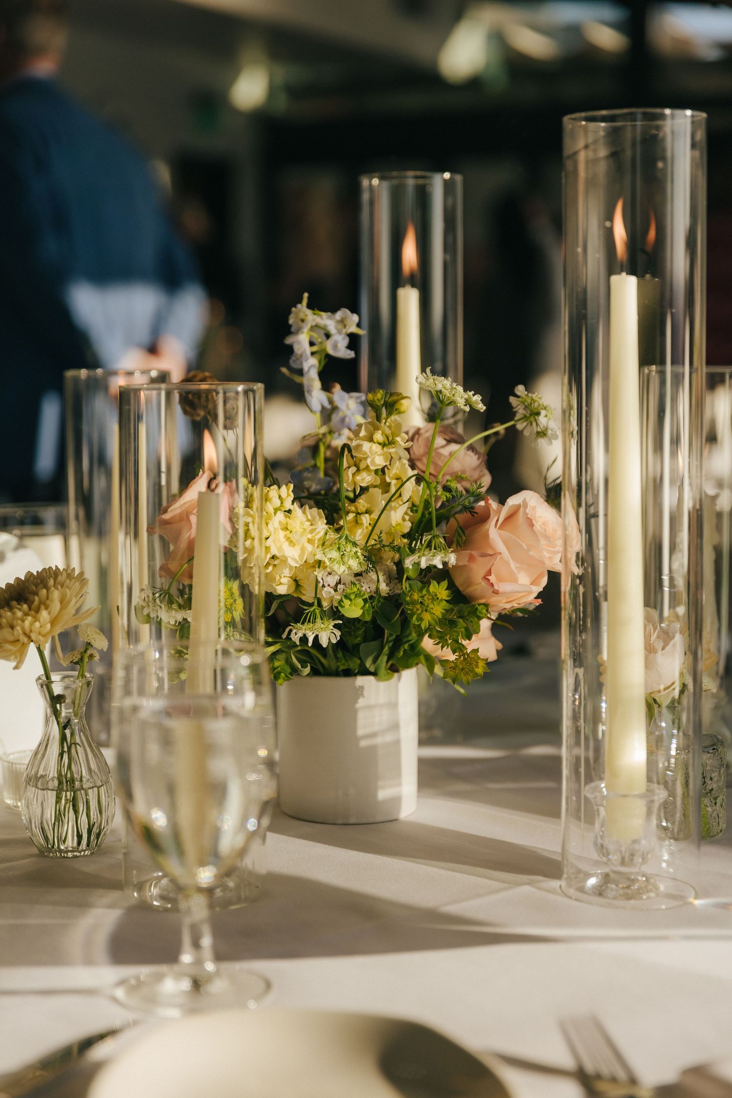 Elegant wedding table decor with glass candleholders and delicate floral arrangements in white and pink.