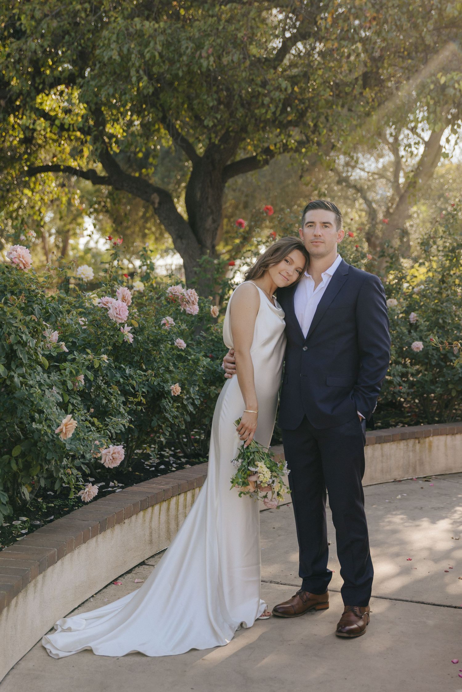 A couple shares romantic moments in a garden setting with blooming roses and trees, captured in multiple poses.