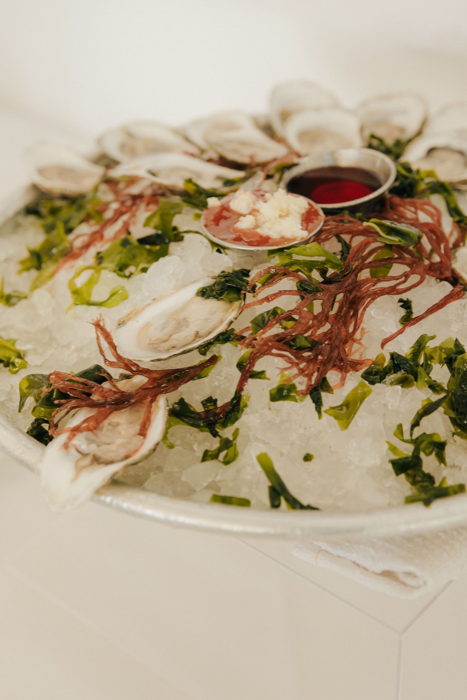 Fresh sliced fish carpaccio garnished with radishes, herbs and olive oil on a white plate.