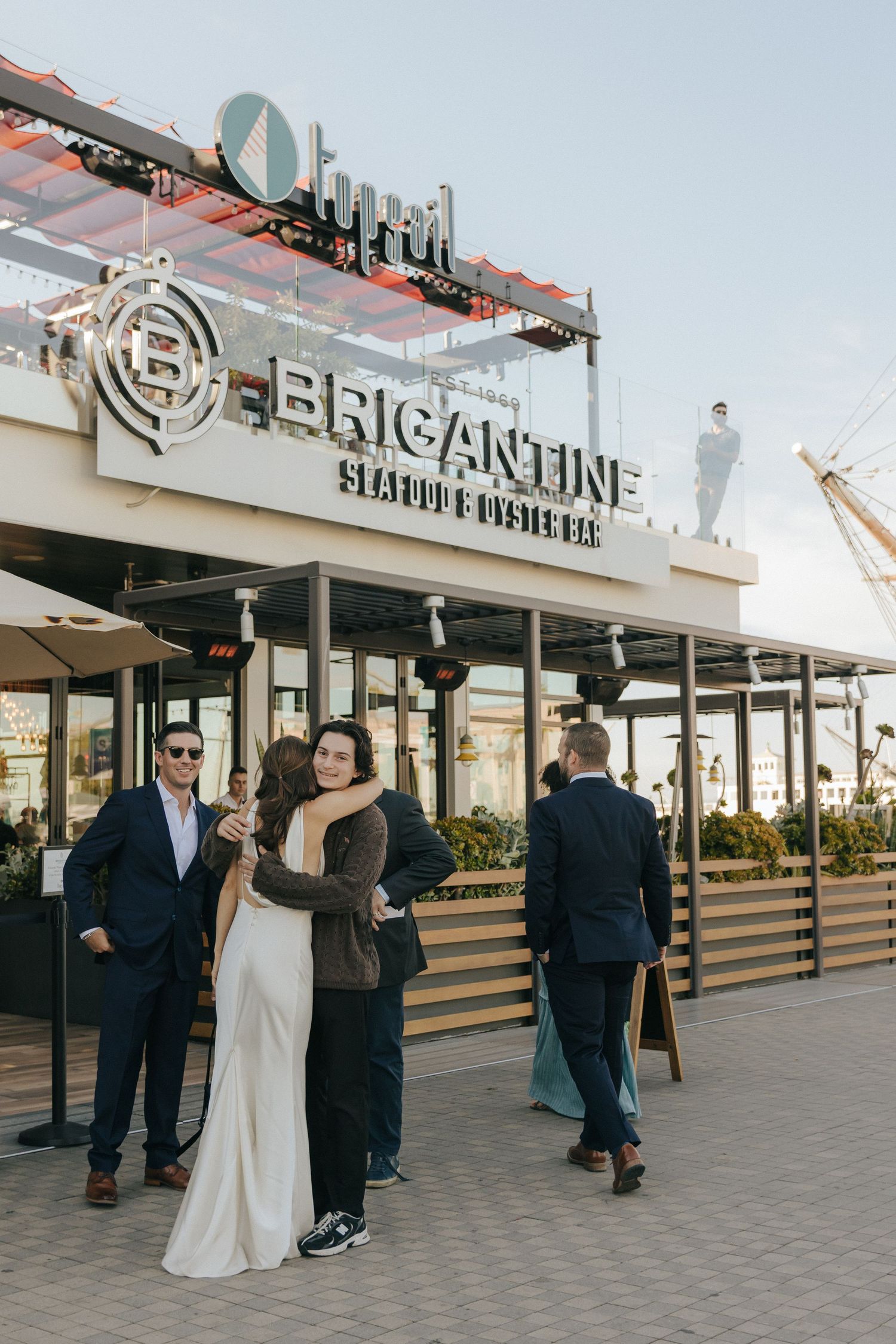 A wedding party poses in front of the Byzantine Seafood Restaurant's illuminated storefront sign.