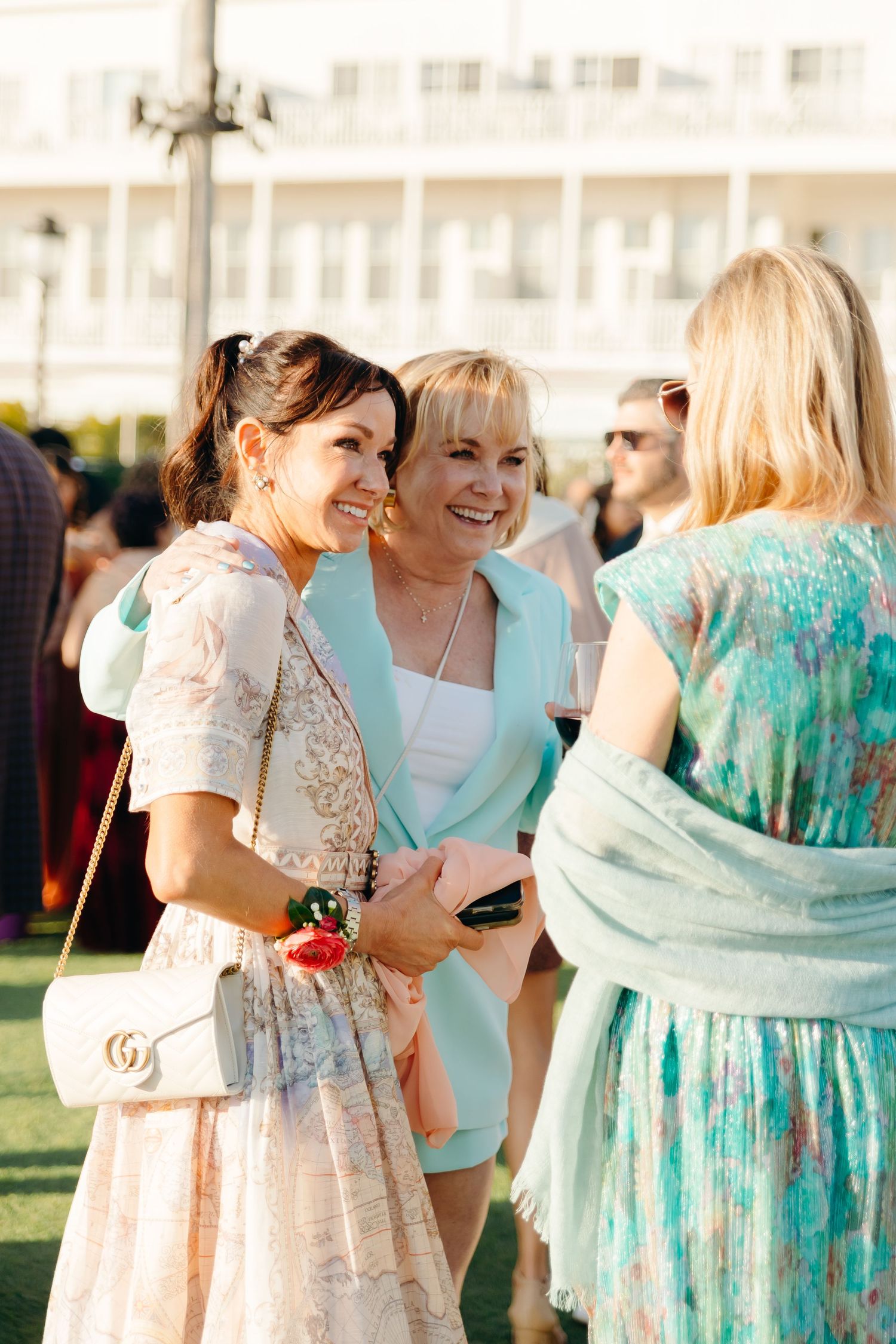 Wedding guests mingling outdoors in colorful summer attire.