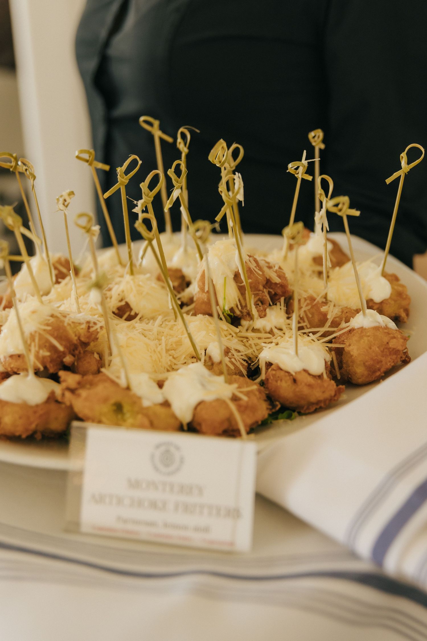 Appetizer platter of bite-sized hors d'oeuvres decorated with golden cocktail picks on a white serving dish.
