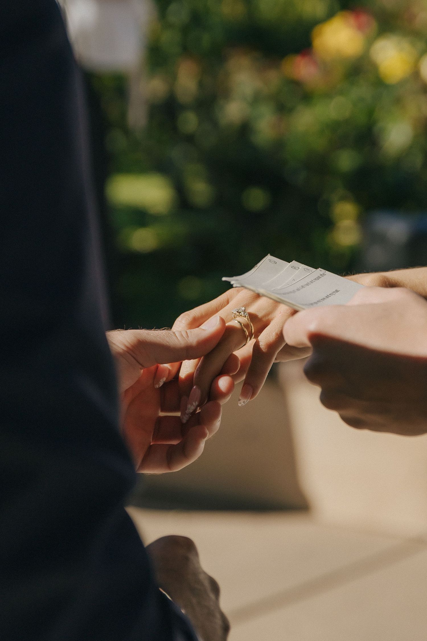 A close-up shot of hands exchanging a business card in natural outdoor lighting.