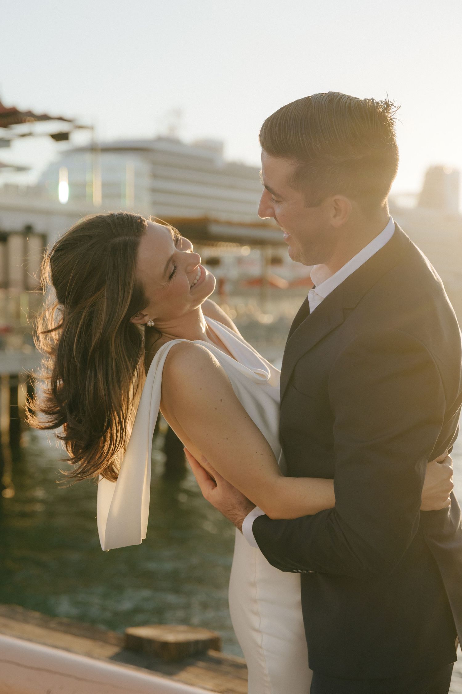 A romantic sunset wedding photoshoot shows a couple embracing and dancing together on a rooftop terrace.