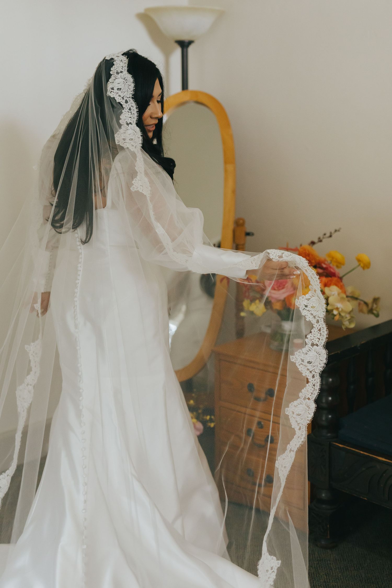 A wedding dress with delicate lace veil hangs elegantly in preparation for a special day.
