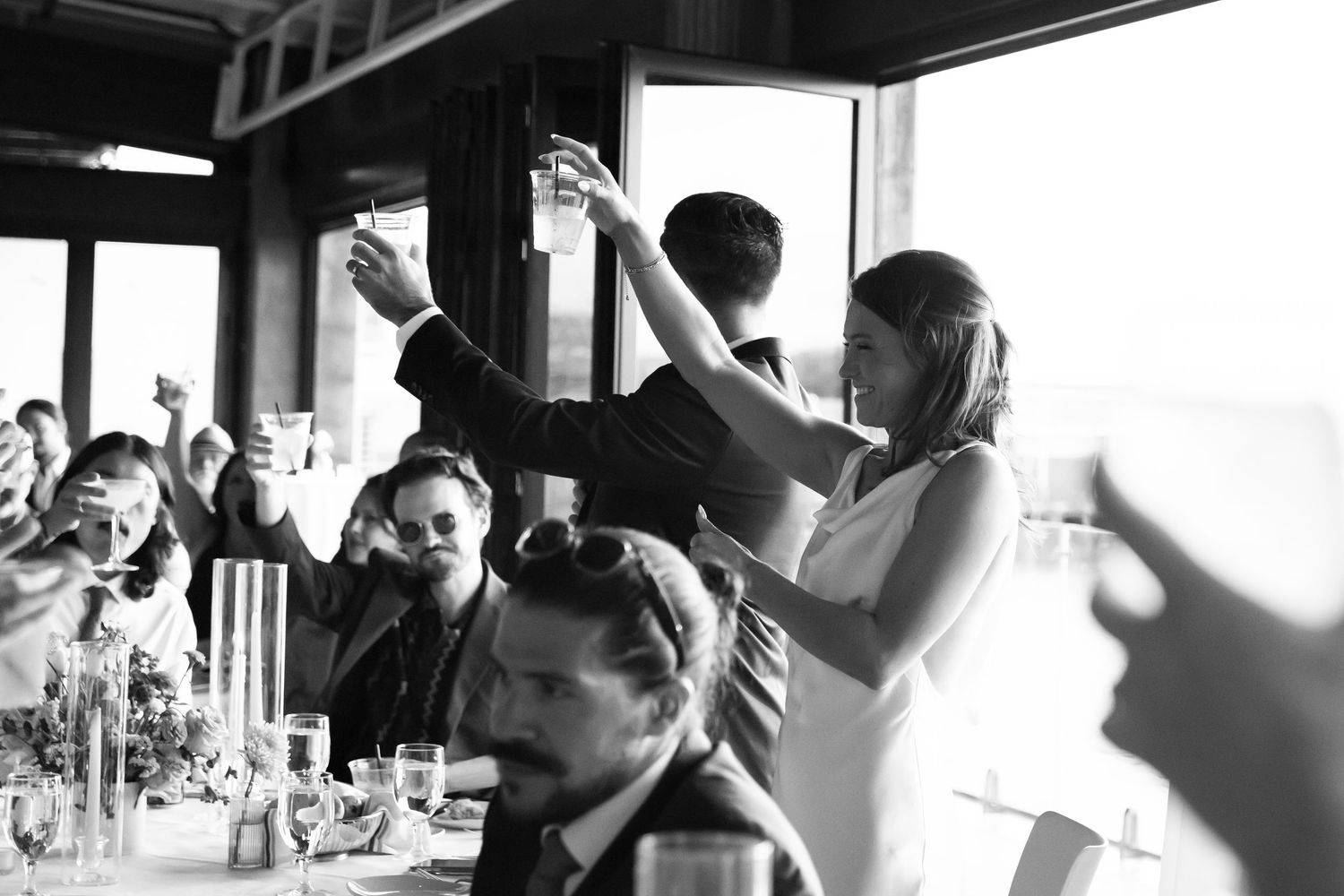 Black and white photo montage showing people raising their hands in various indoor settings and social gatherings.