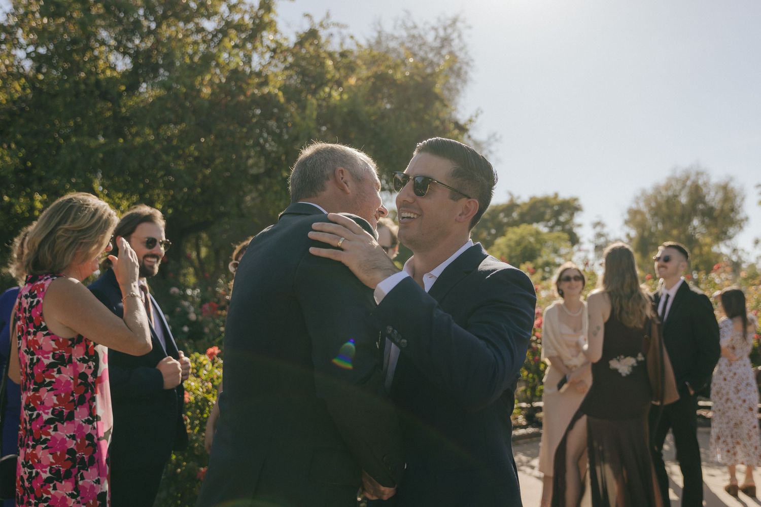 Wedding guests celebrate and dance together during an outdoor sunset reception at a vineyard.
