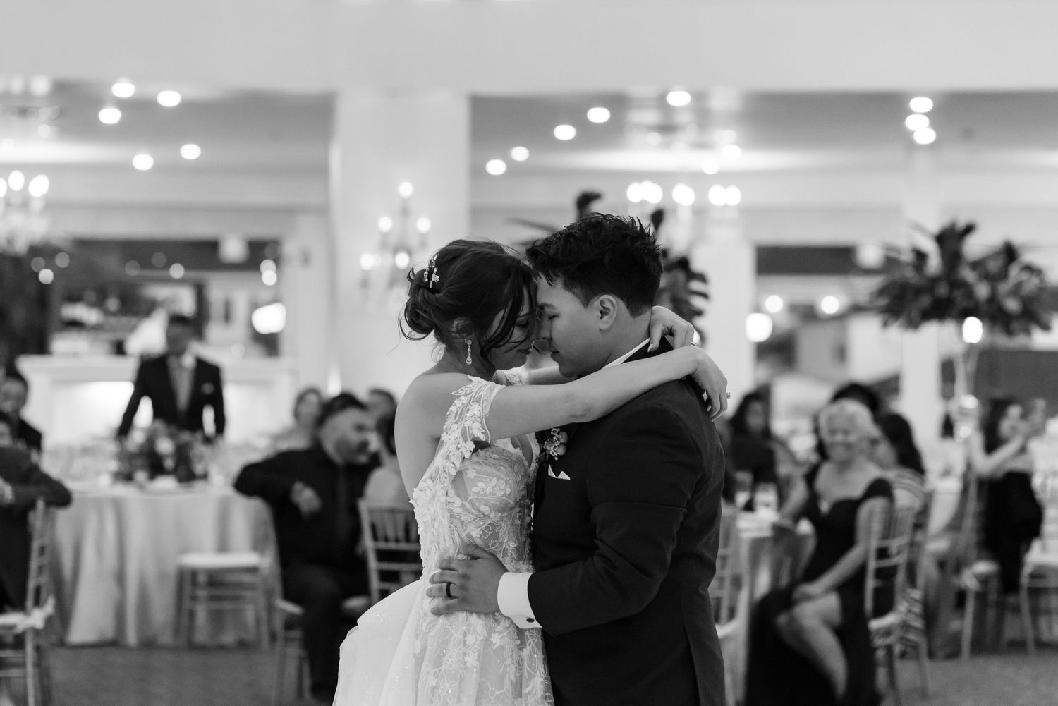 A couple shares their first dance in an elegant reception hall with twinkling lights.