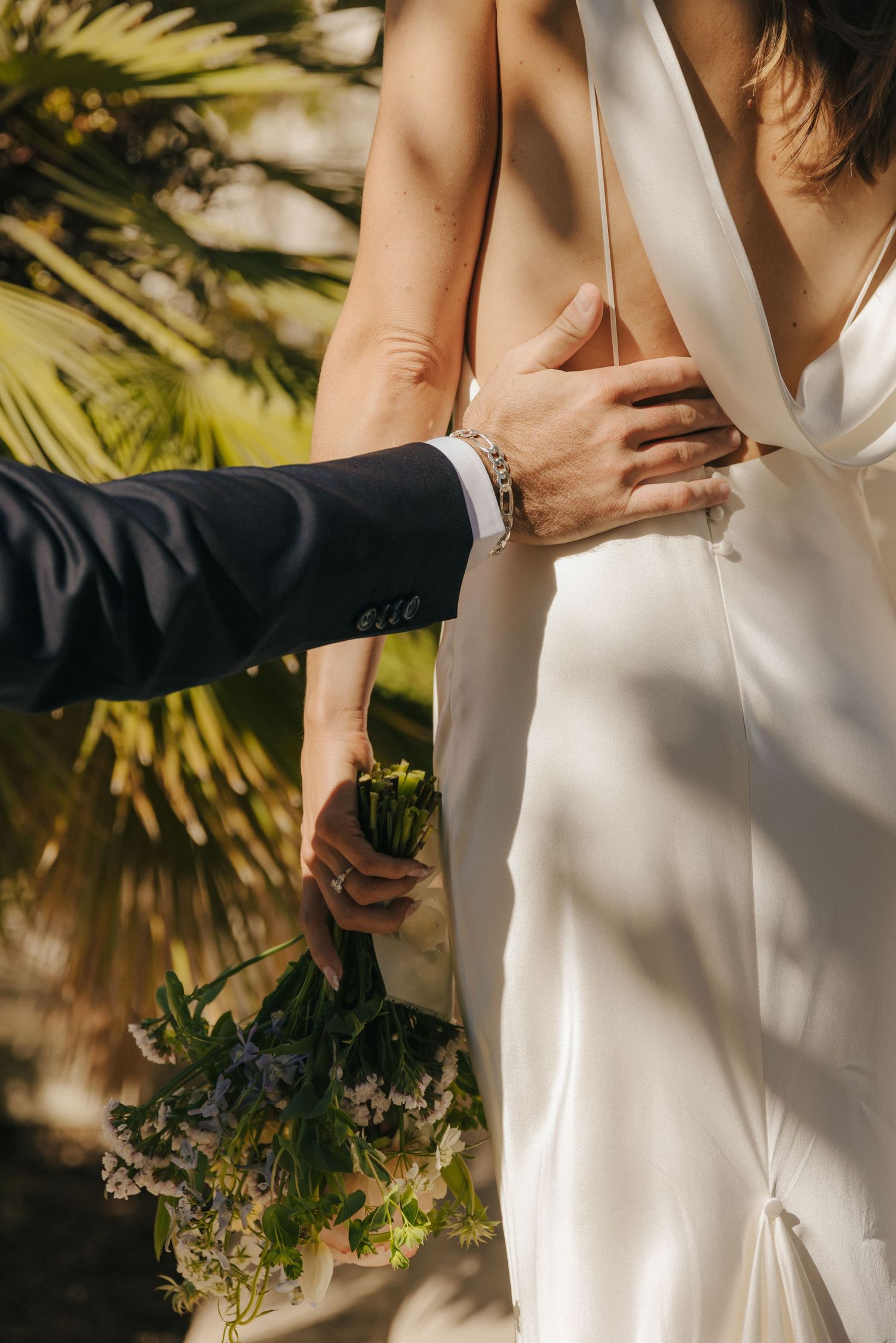 Close-up shots of a couple in wedding attire embracing against a tropical palm background in warm sunlight.