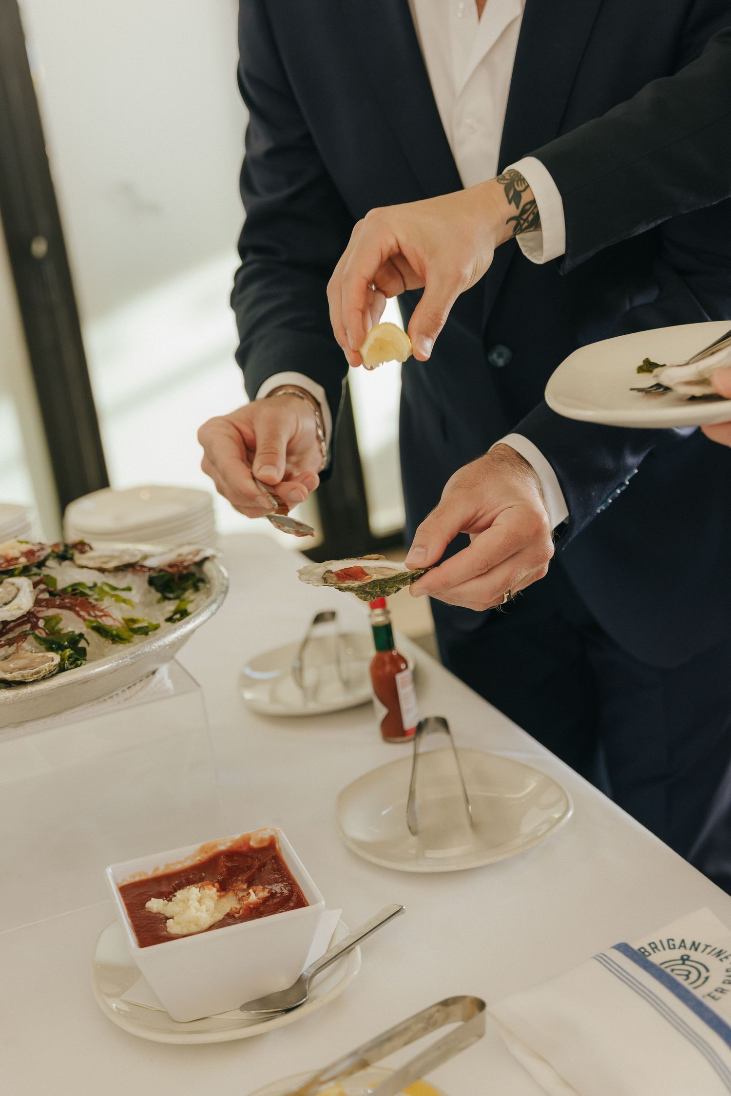Person in navy suit dining at upscale restaurant with tomato soup and salad plates on white tablecloth.