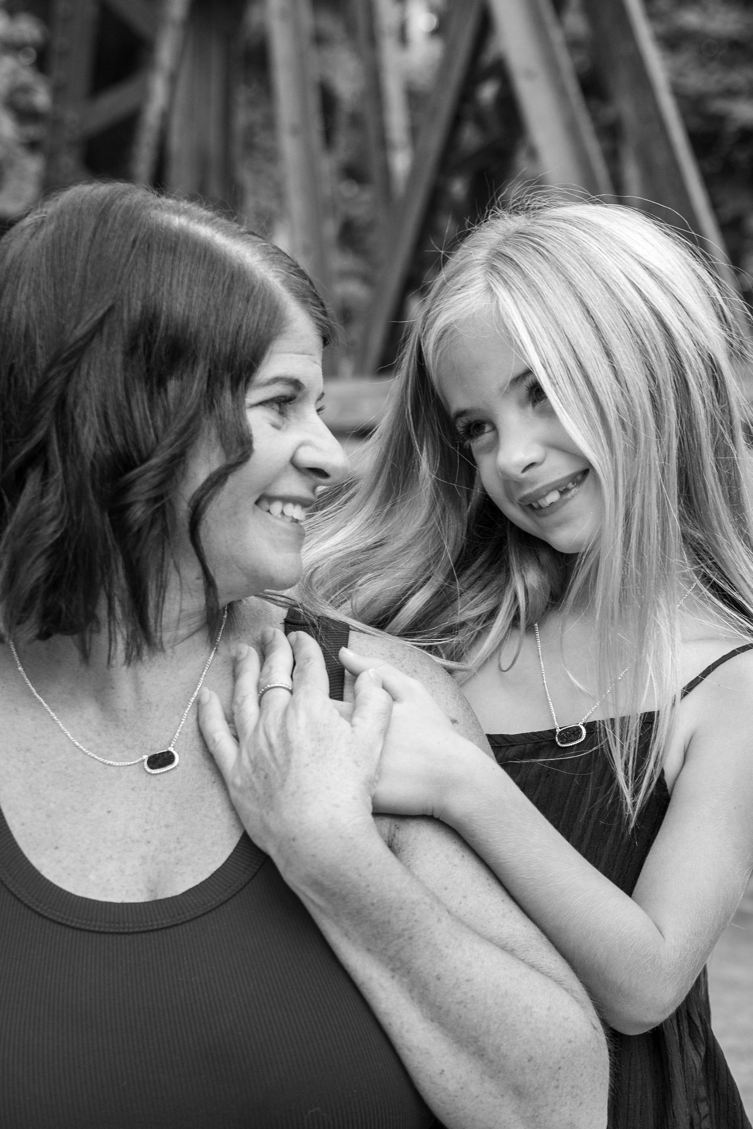 Black and white photo of a smiling woman and young blonde girl sharing a tender moment outdoors.