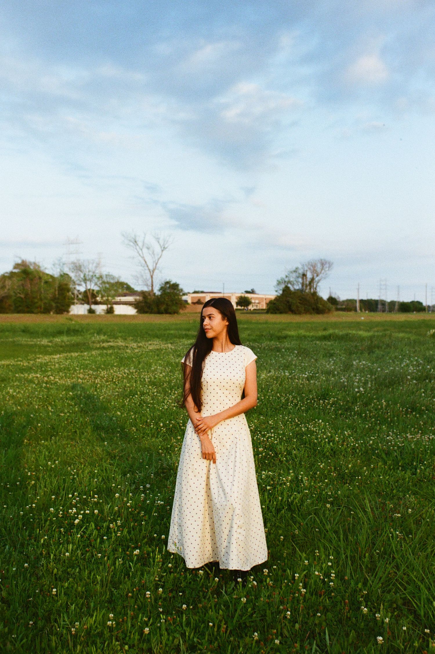 a girl standing in the open green field looking away, photographed in film
