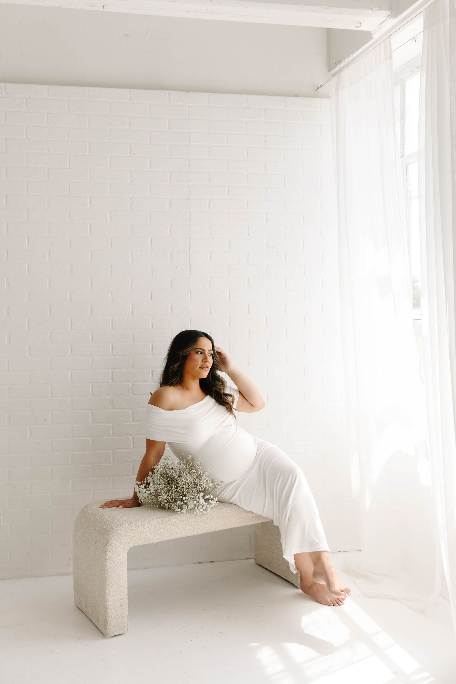 maternity portrait of mom sitting on a bench facing the window