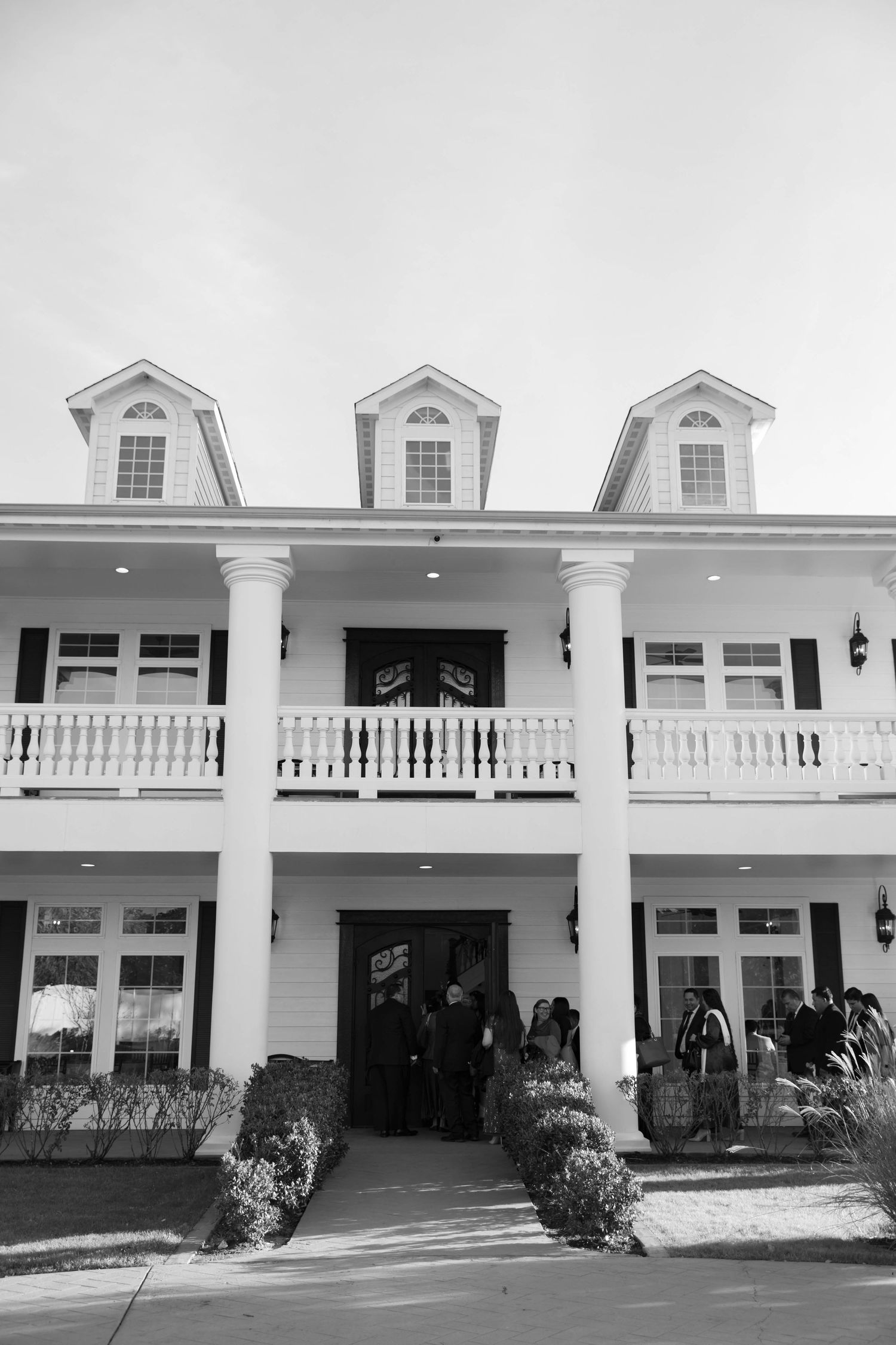 Black and white photo of a classic southern style wedding venue with white columns and large front porch.