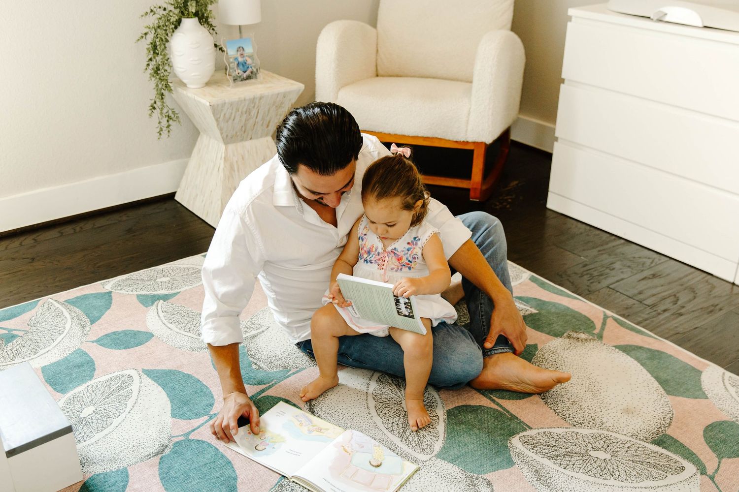 a candid photo of a father reading while a toddler sits on his lap cozy family moment