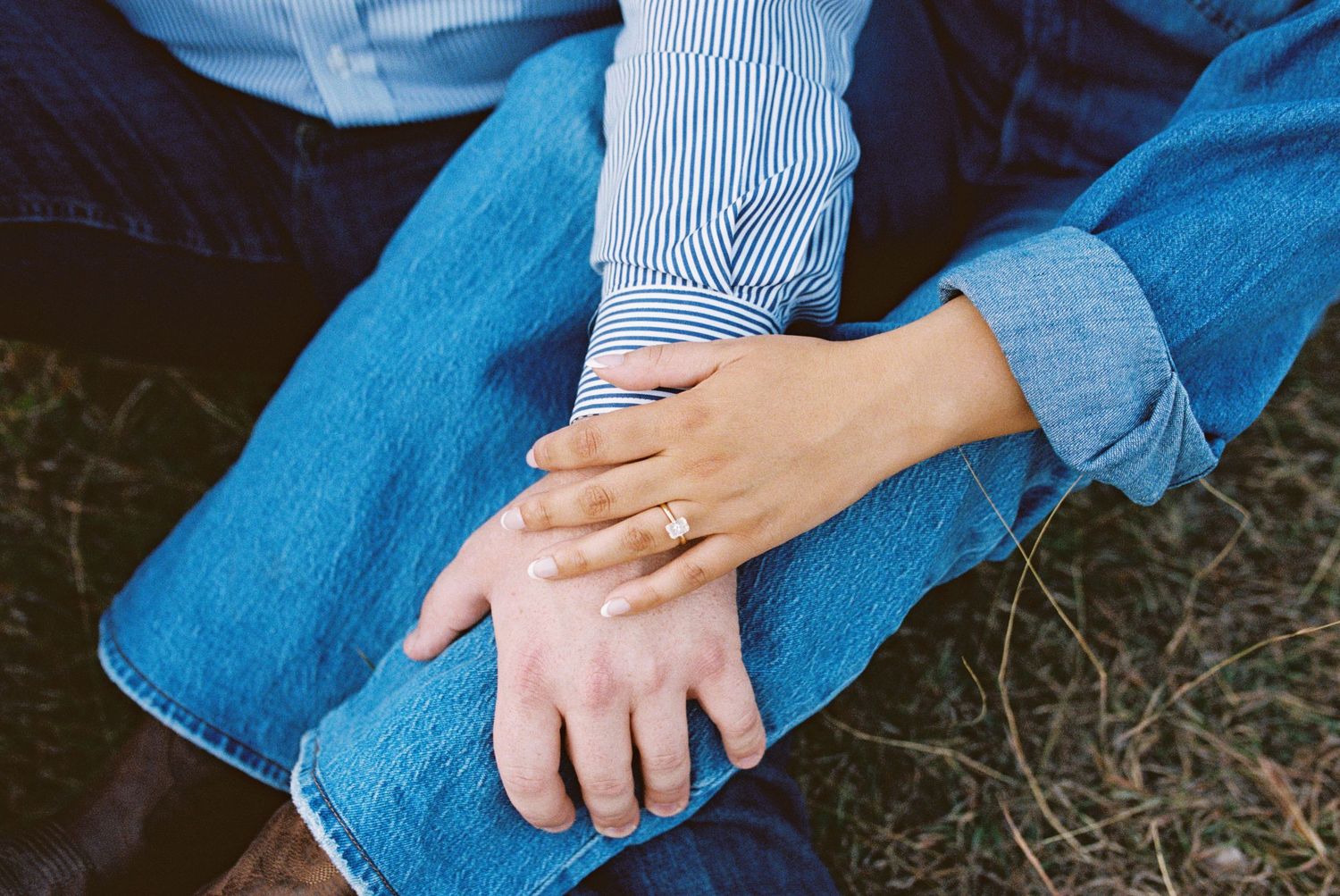 Close up photo of couples hands over one another showcasing the engagement ring.