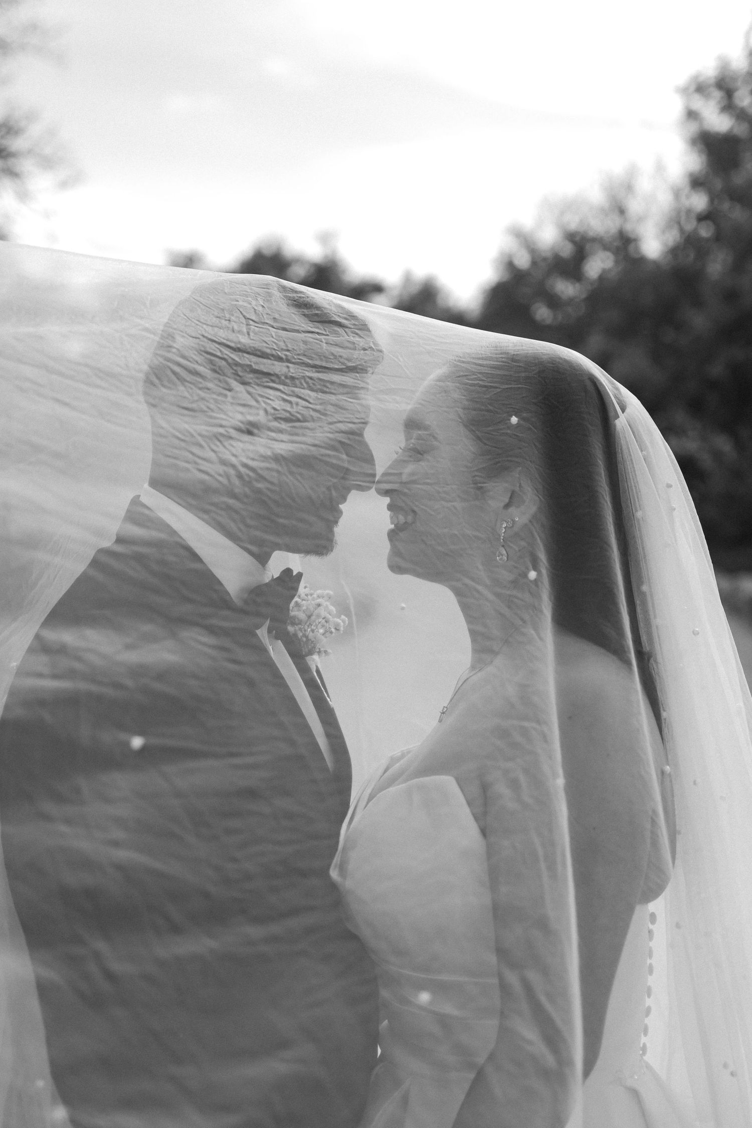 black and white wedding portrait of a couple under veil.