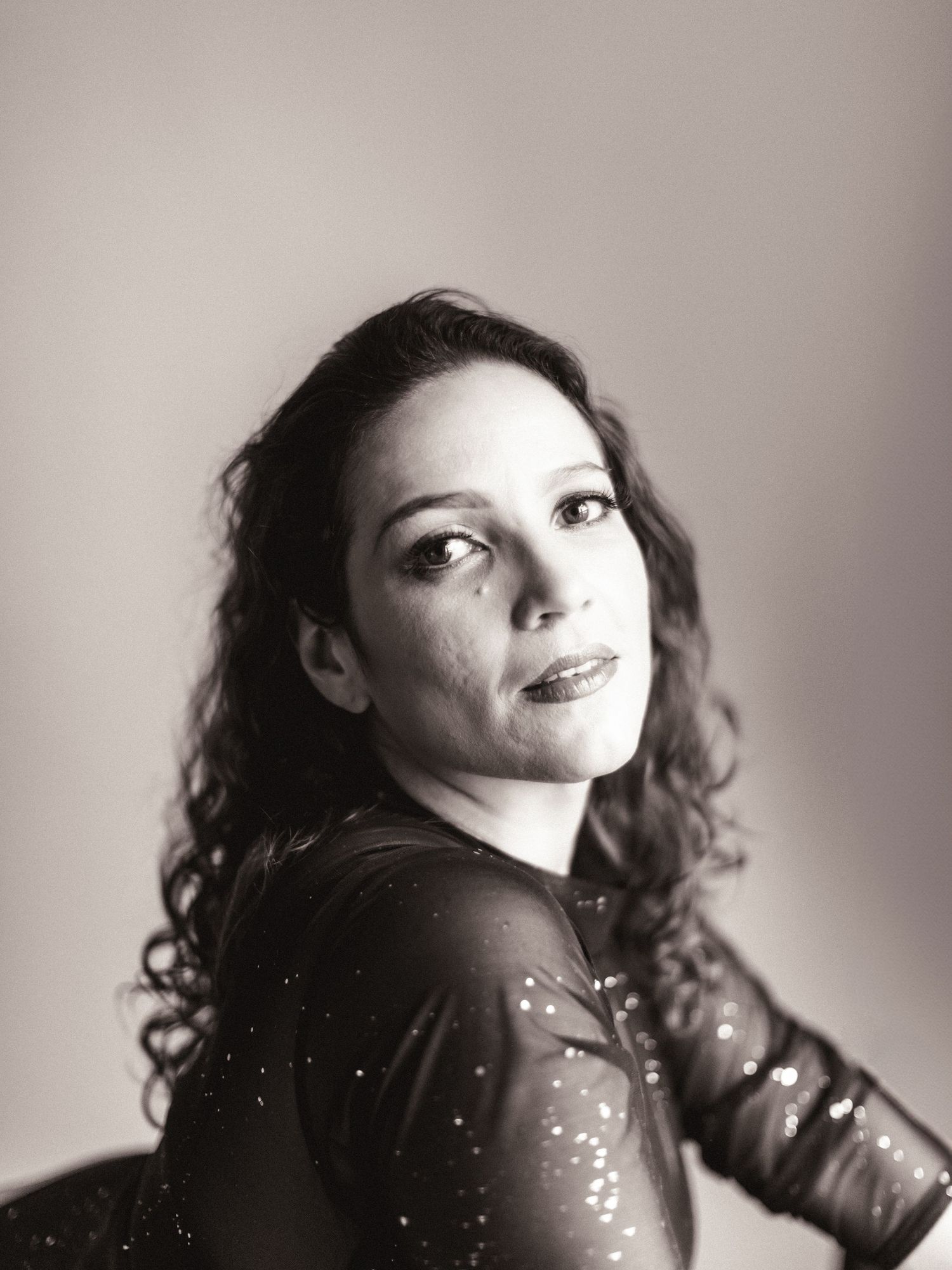 Artistic black and white intimate portrait showing movement and expression in a dramatic studio setting of a woman.