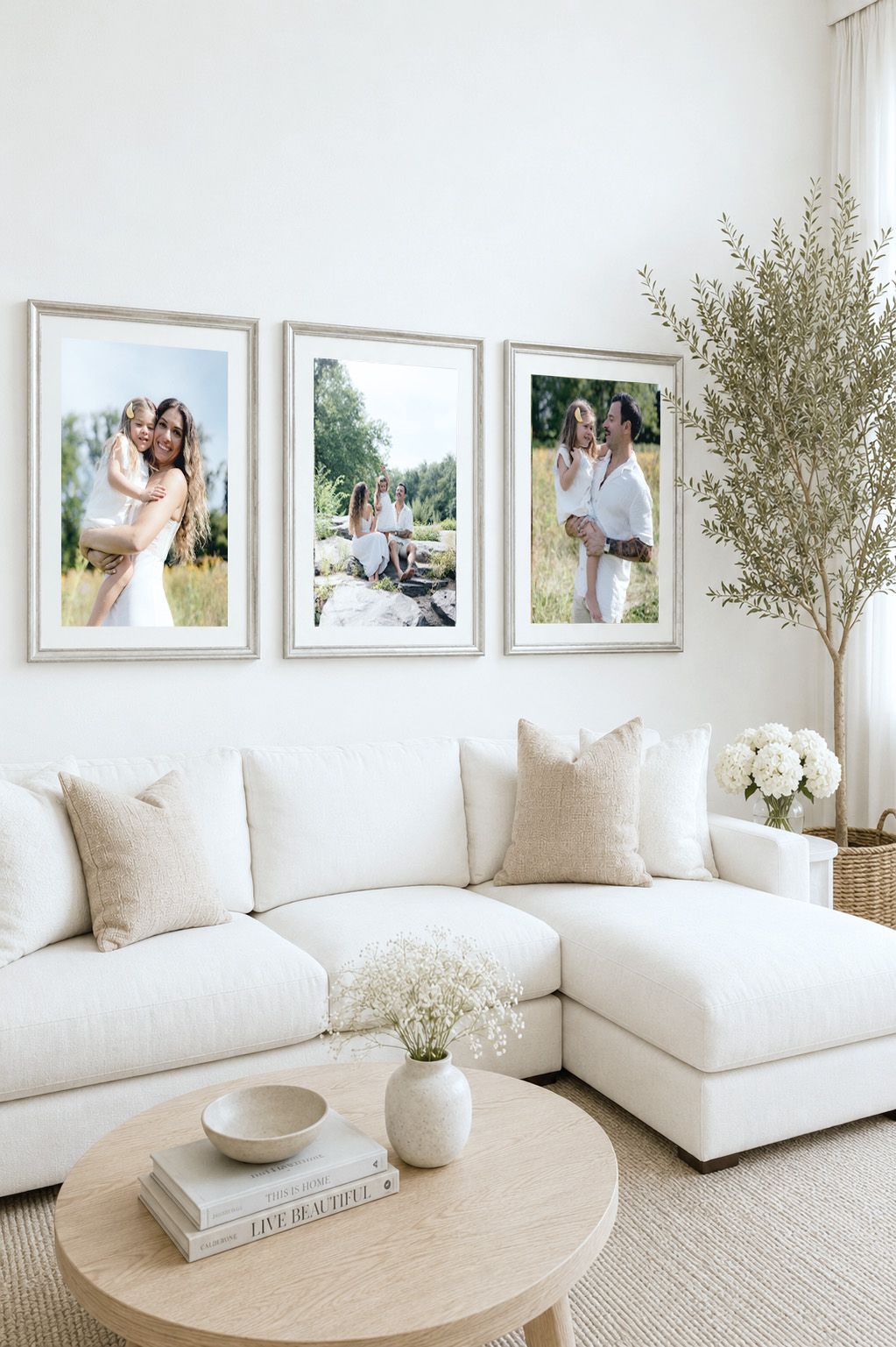 Bright living room with white sectional sofa, round wood coffee table, and three framed family photos on the wall.