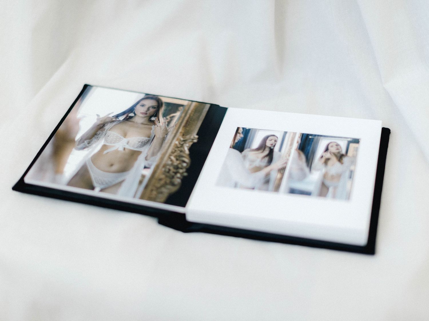 Open photo album displaying boudoir portraits of a woman in white lingerie, elegantly arranged on ivory fabric.