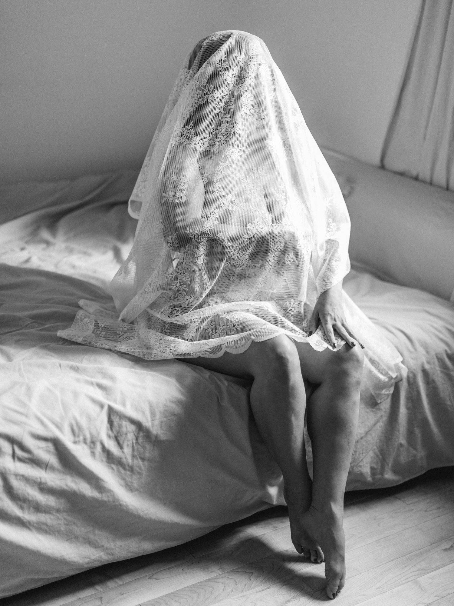 A photo of black and white photos showing a woman in a white dress crouching and moving on a bed.