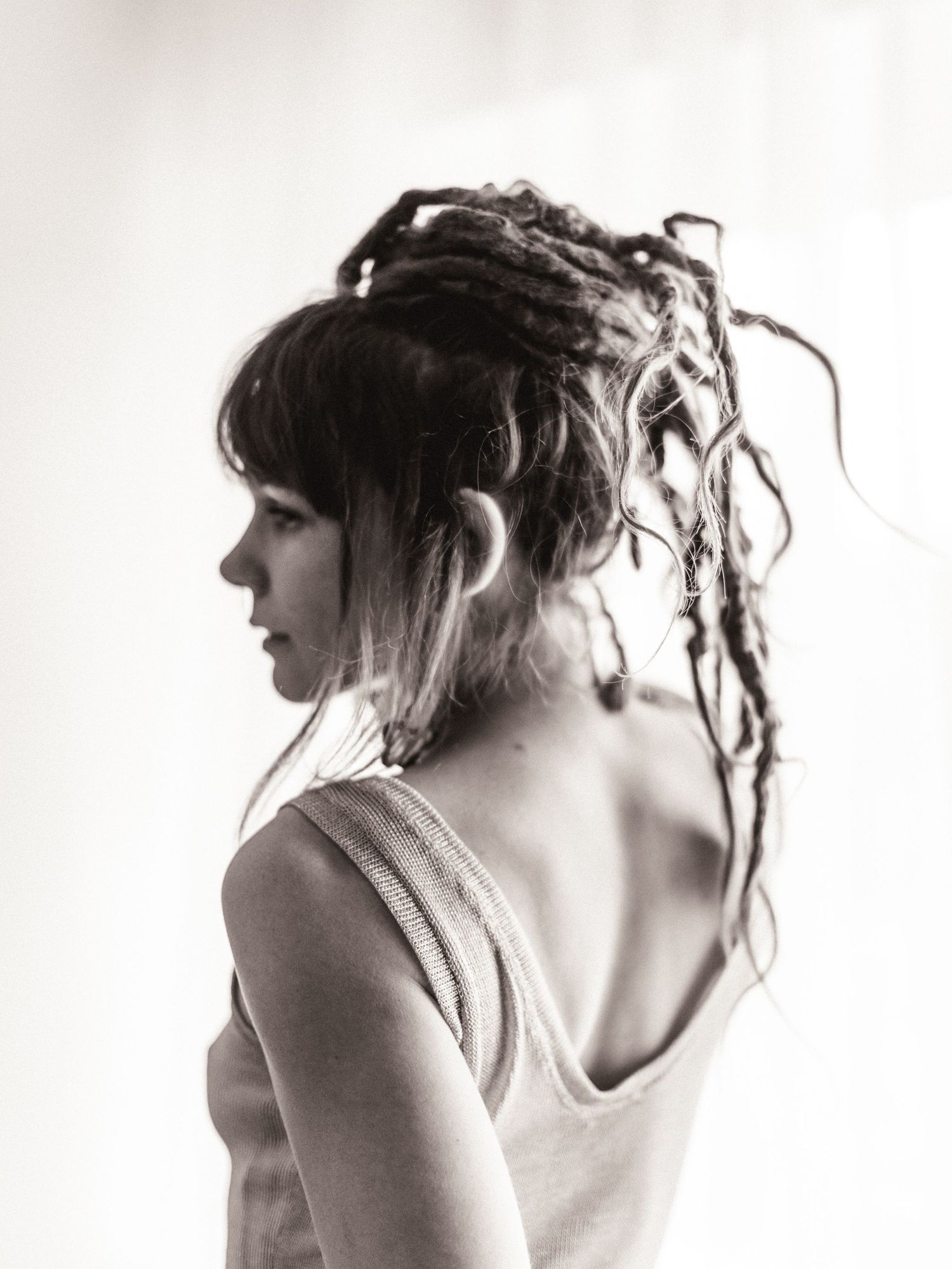Black and white profile portrait of a young woman with dreadlocks wearing a tank top.