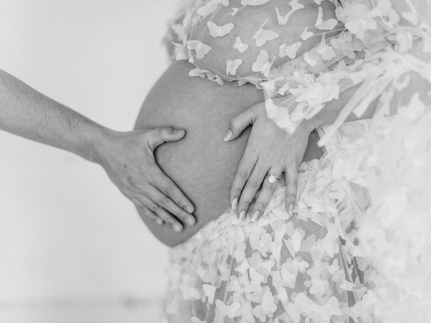 Philadelphia maternity photo of pregnant woman in lace dress with hands cradling baby bump.