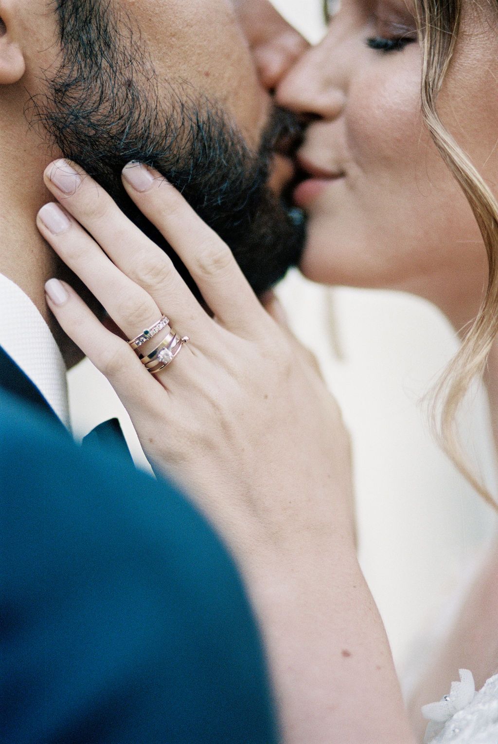 Close-up of bride and groom kissing with wedding rings visible on bride's hand.