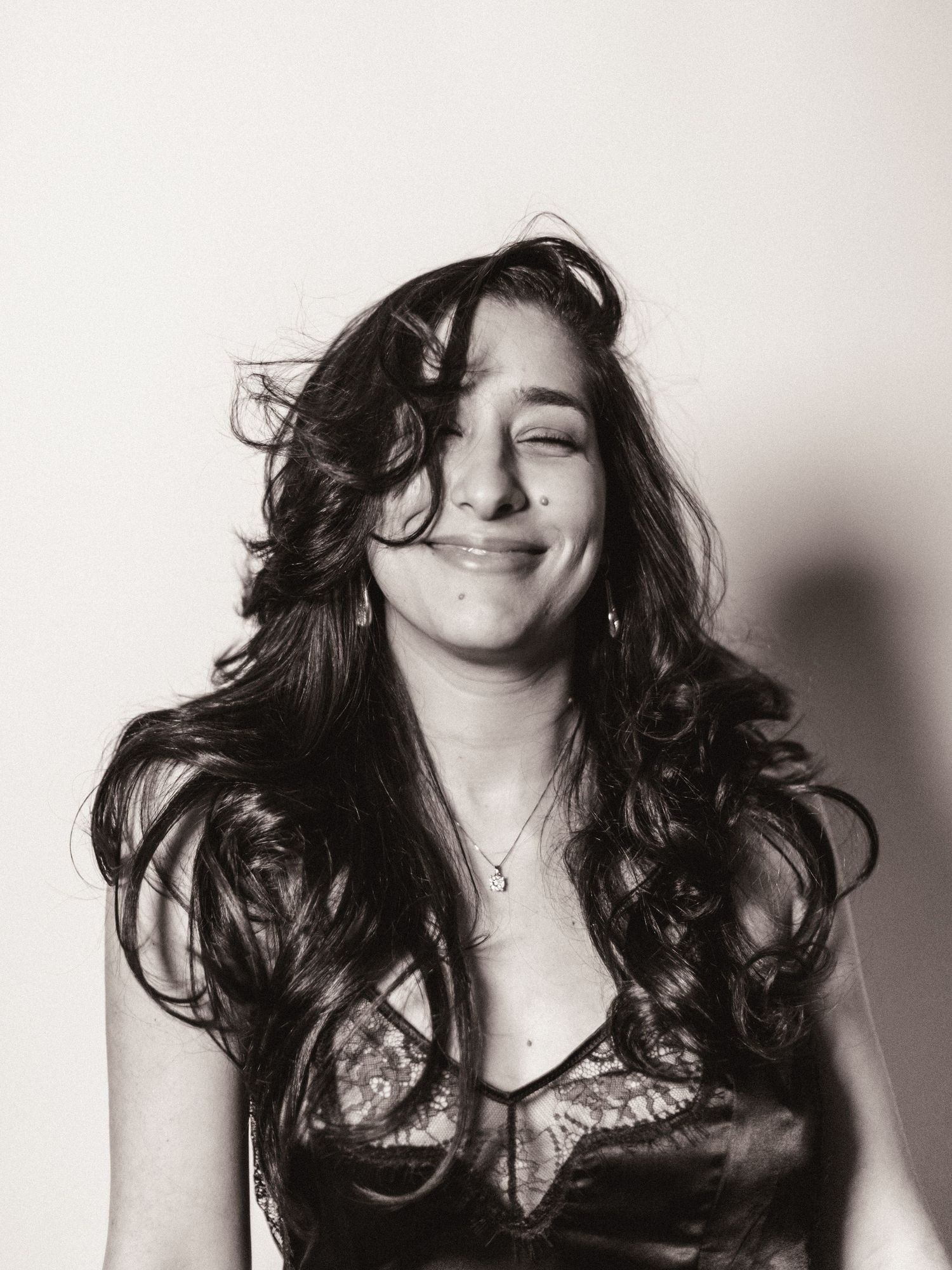 Black and white portrait of a young woman with flowing dark hair, smiling with eyes closed.
