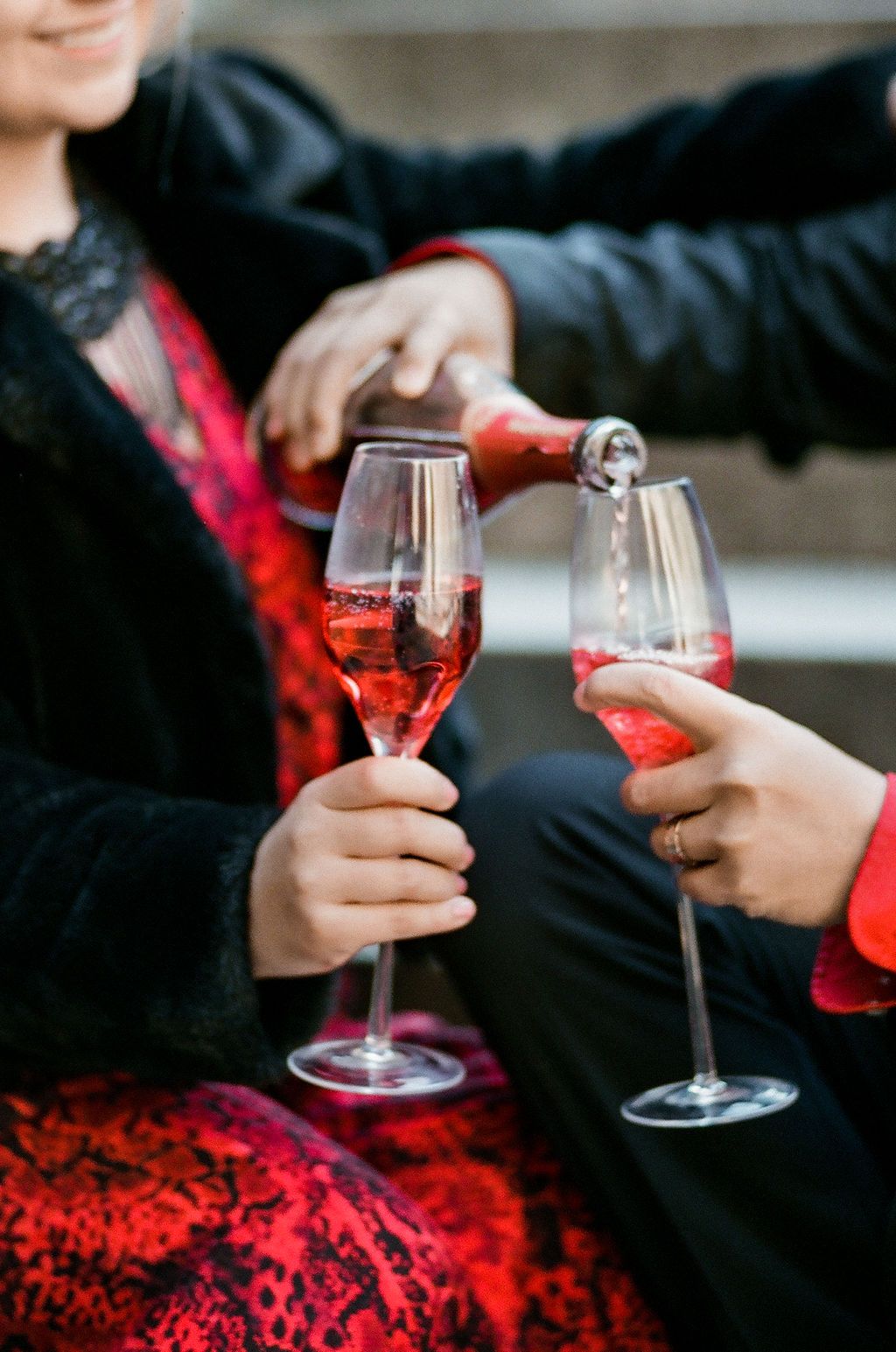Couple pouring pink champagne into elegant flutes during a romantic celebration.