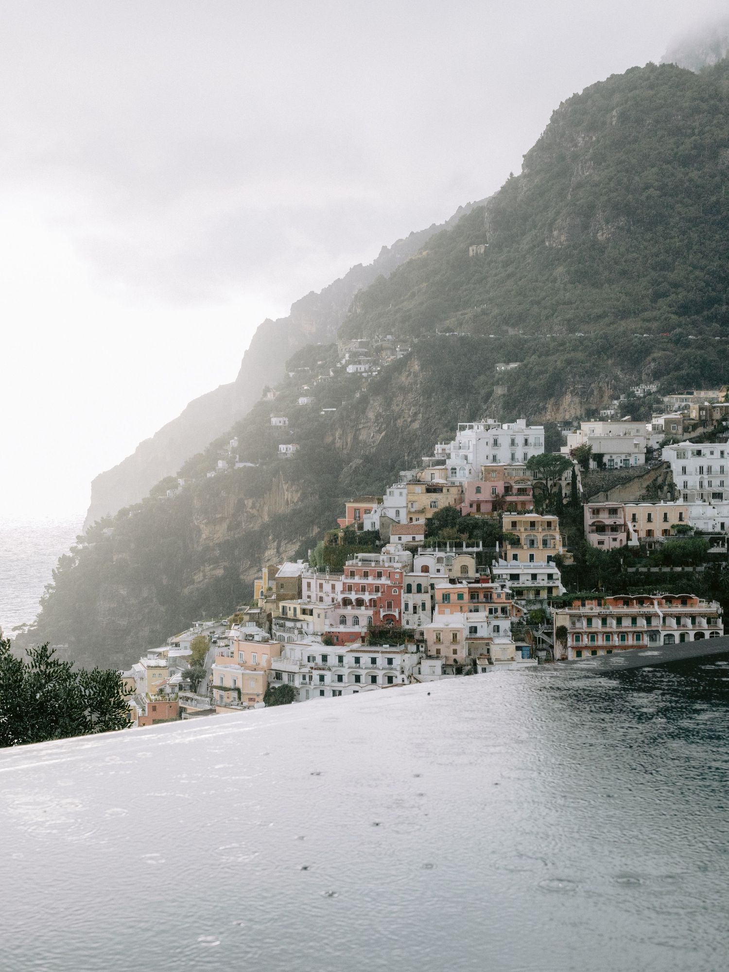 Misty aerial view of colorful Positano village on Amalfi Coast cliffside overlooking the sea.