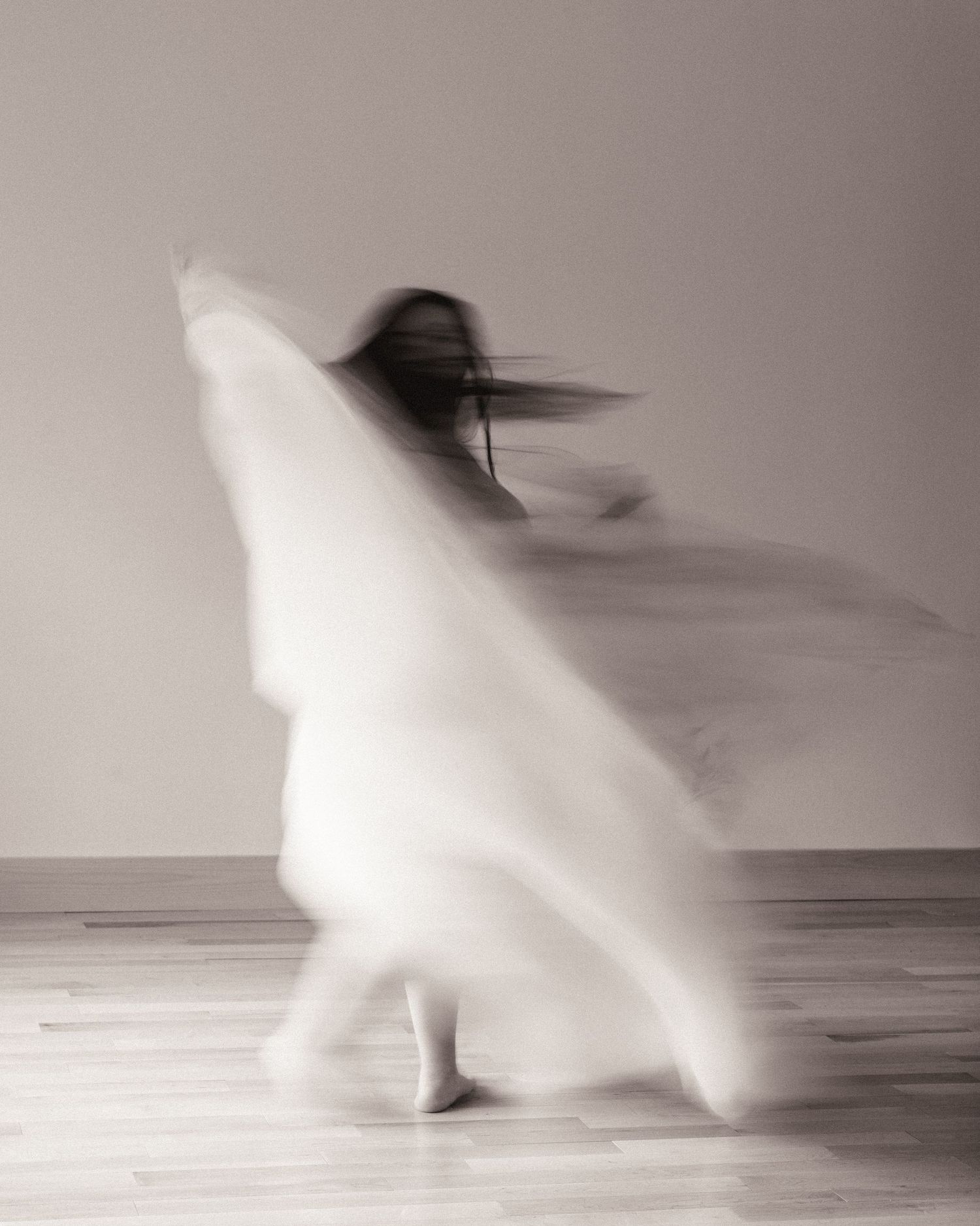 Blurred motion of a dancer in flowing white fabric captured in black and white Philadelphia maternity photography.
