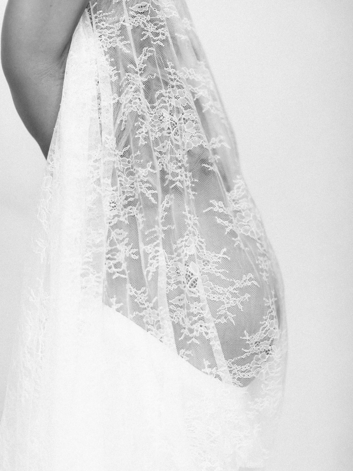 Close-up black and white detail of intricate floral lace wedding veil draping elegantly.